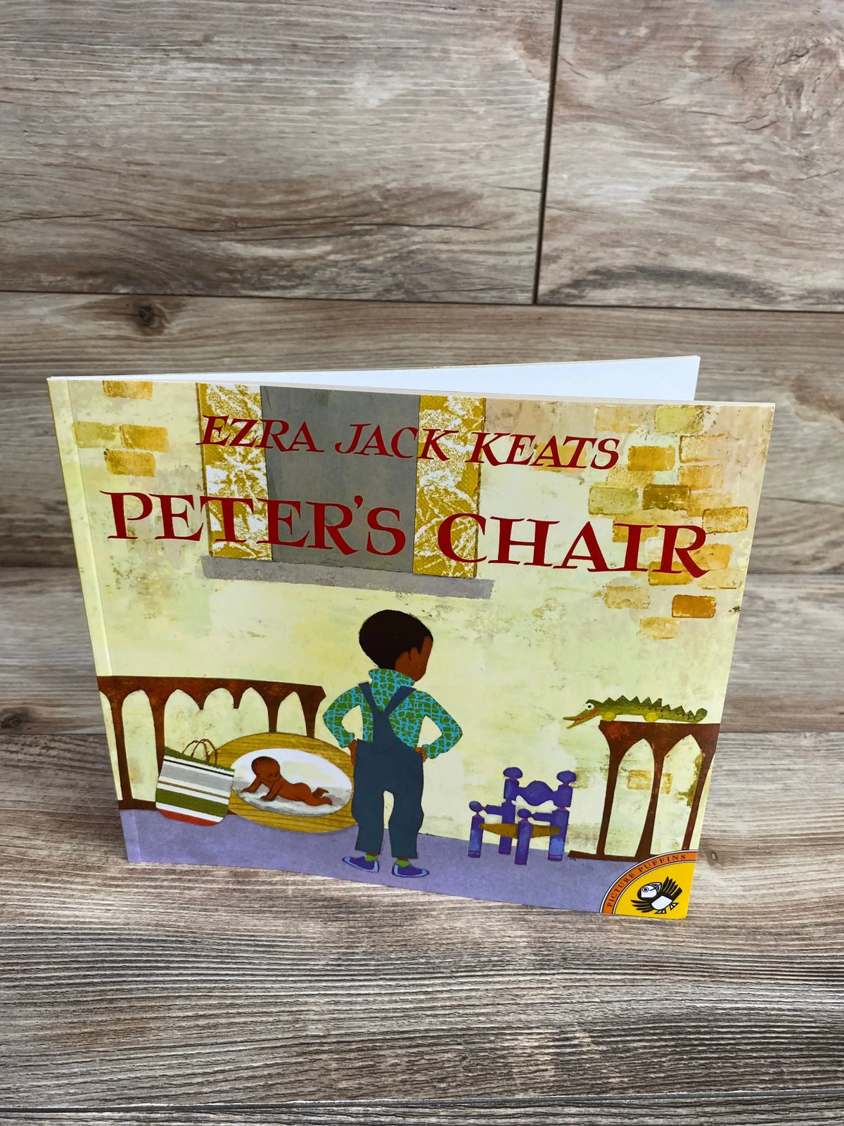 Cover of Ezra Jack Keats' children's book Peter's Chair featuring a boy standing in front of a small purple chair and alligator toy