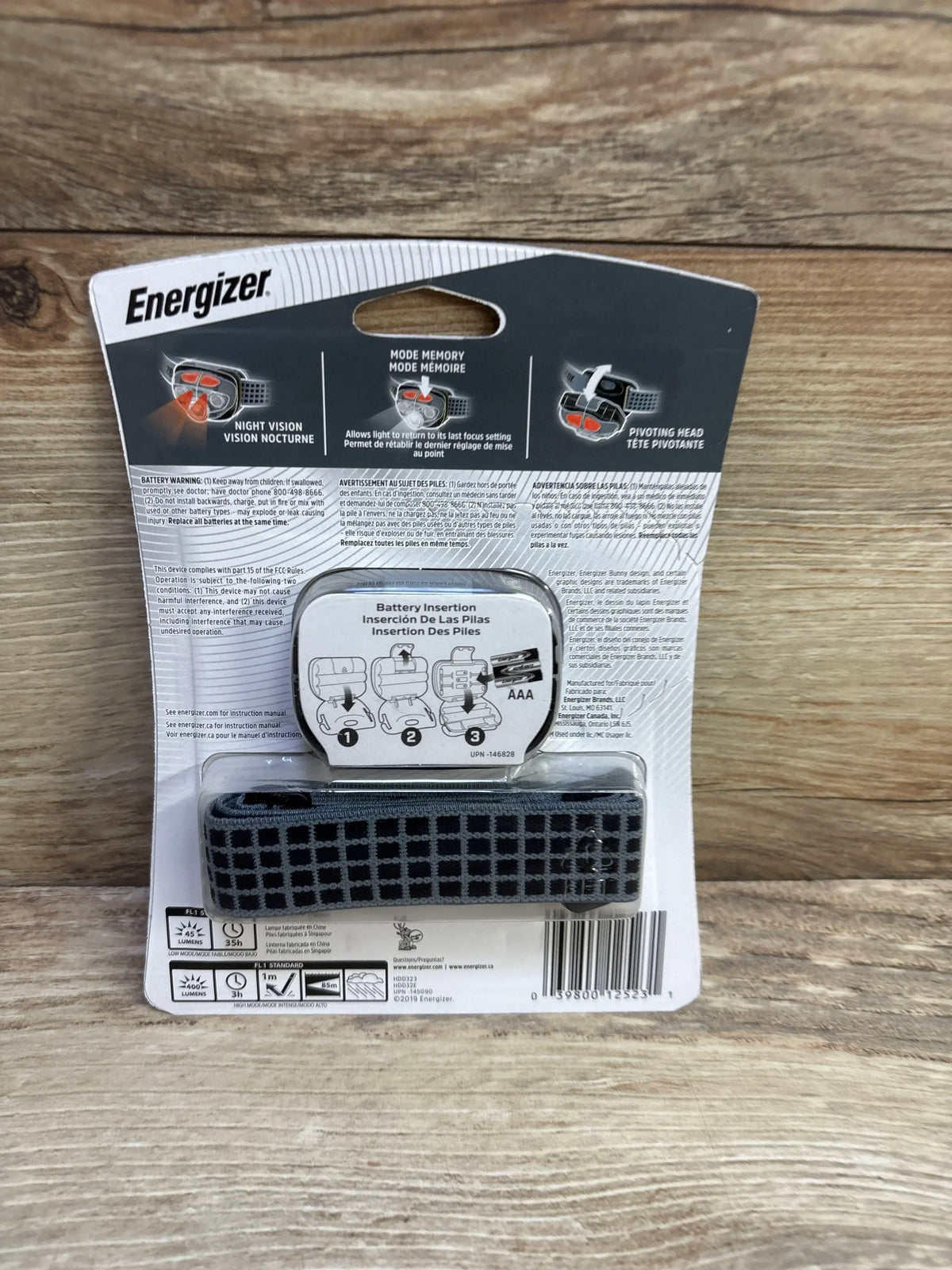 Back view of Energizer Vision HD Plus Focus Headlamp with Batteries showcasing black headband in retail packaging on a wood surface