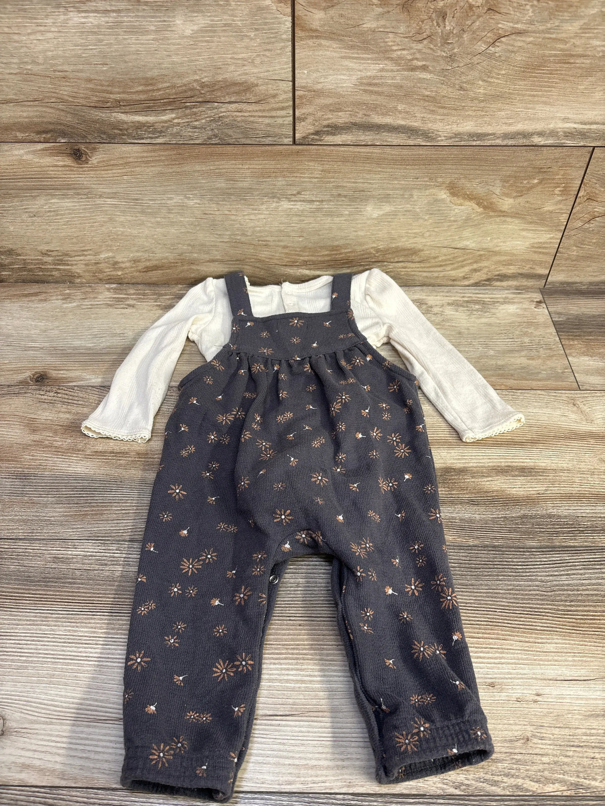 Front view of Grayson Mini two piece set showcasing ivory puff sleeve bodysuit with floral overalls on wood flooring