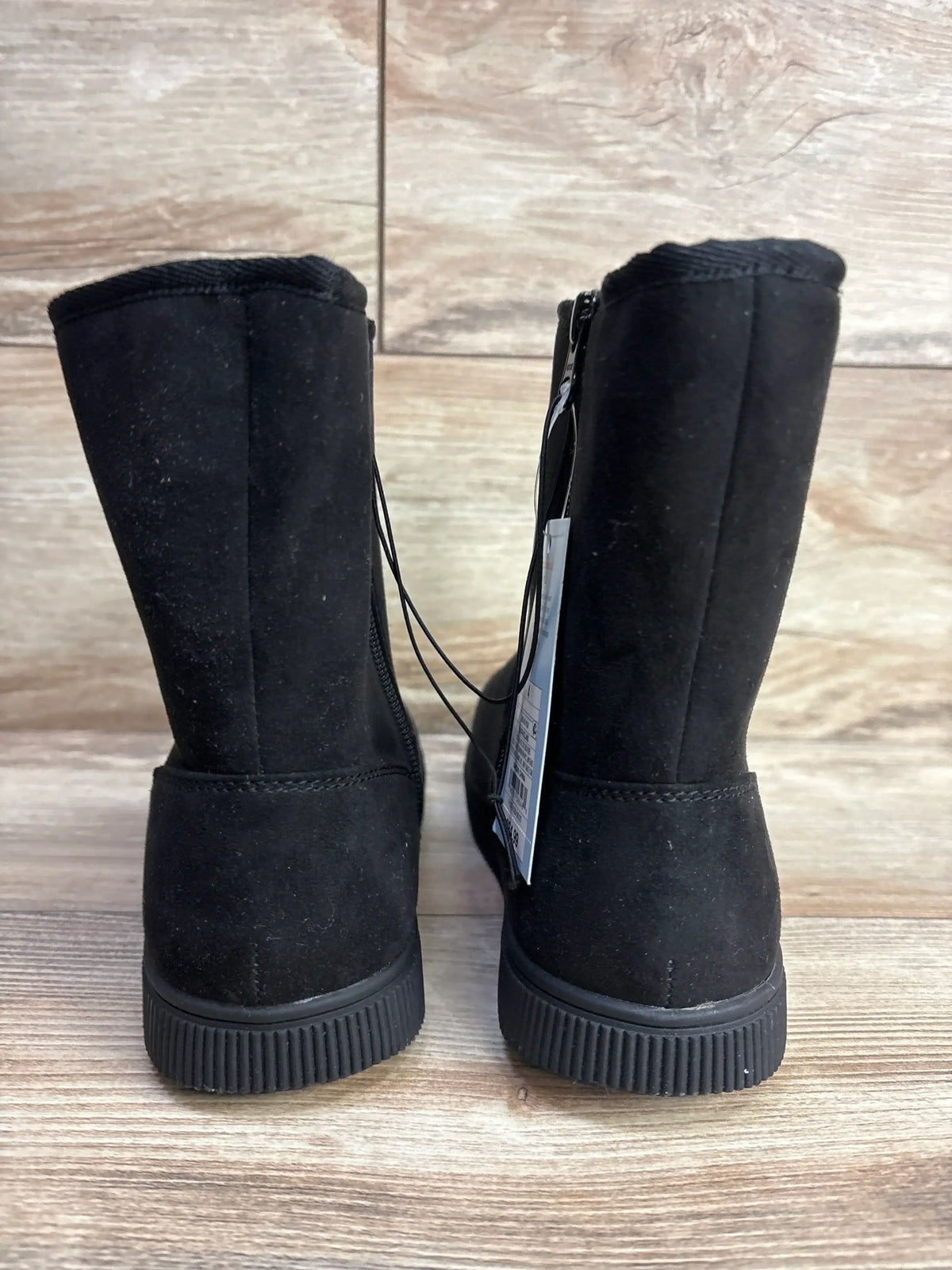 Rear view of Cat and Jack Holland shearling-style black kids boots with rubber soles, back zipper, and tag on wood floor