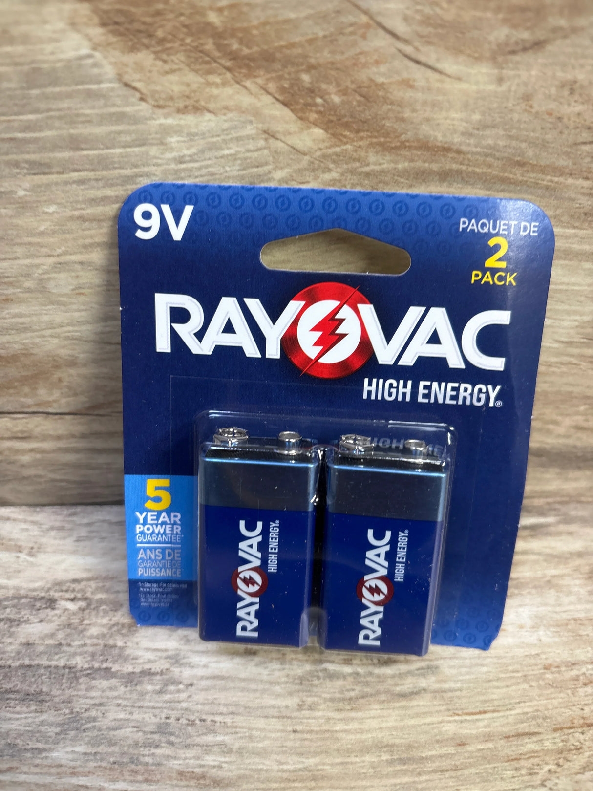 Front view of Rayovac High Energy 9V batteries 2-pack in blister card showing 5 year power guarantee on wood background
