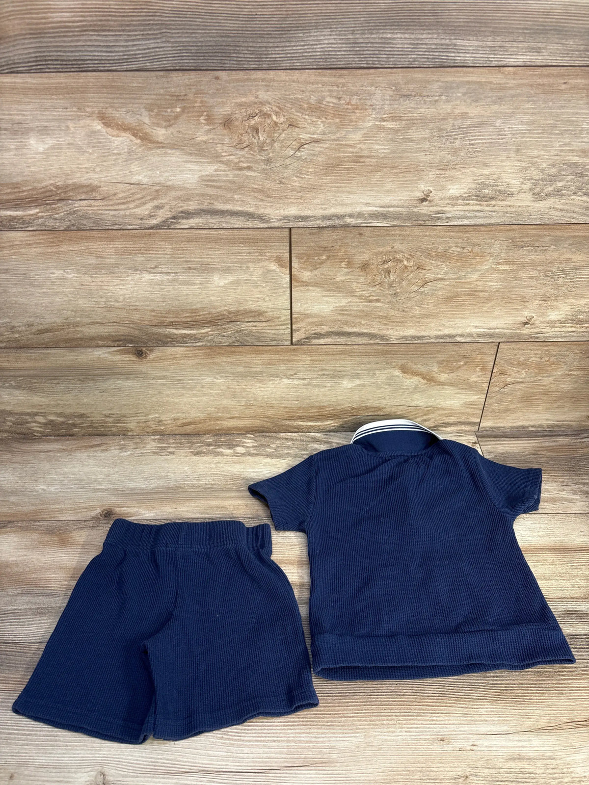 Top view of Tahari waffle knit quarter-zip shirt and matching shorts set showcasing navy fabric on a wood background