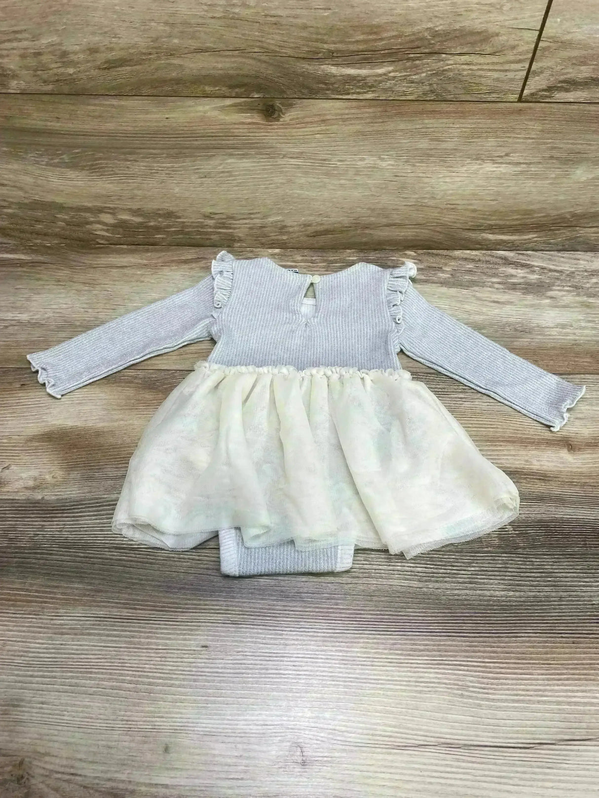 Flat lay of gray rib-knit metallic Old Navy baby bodysuit dress 3-6m showing tulle skirt and ruffle shoulders on wood floor