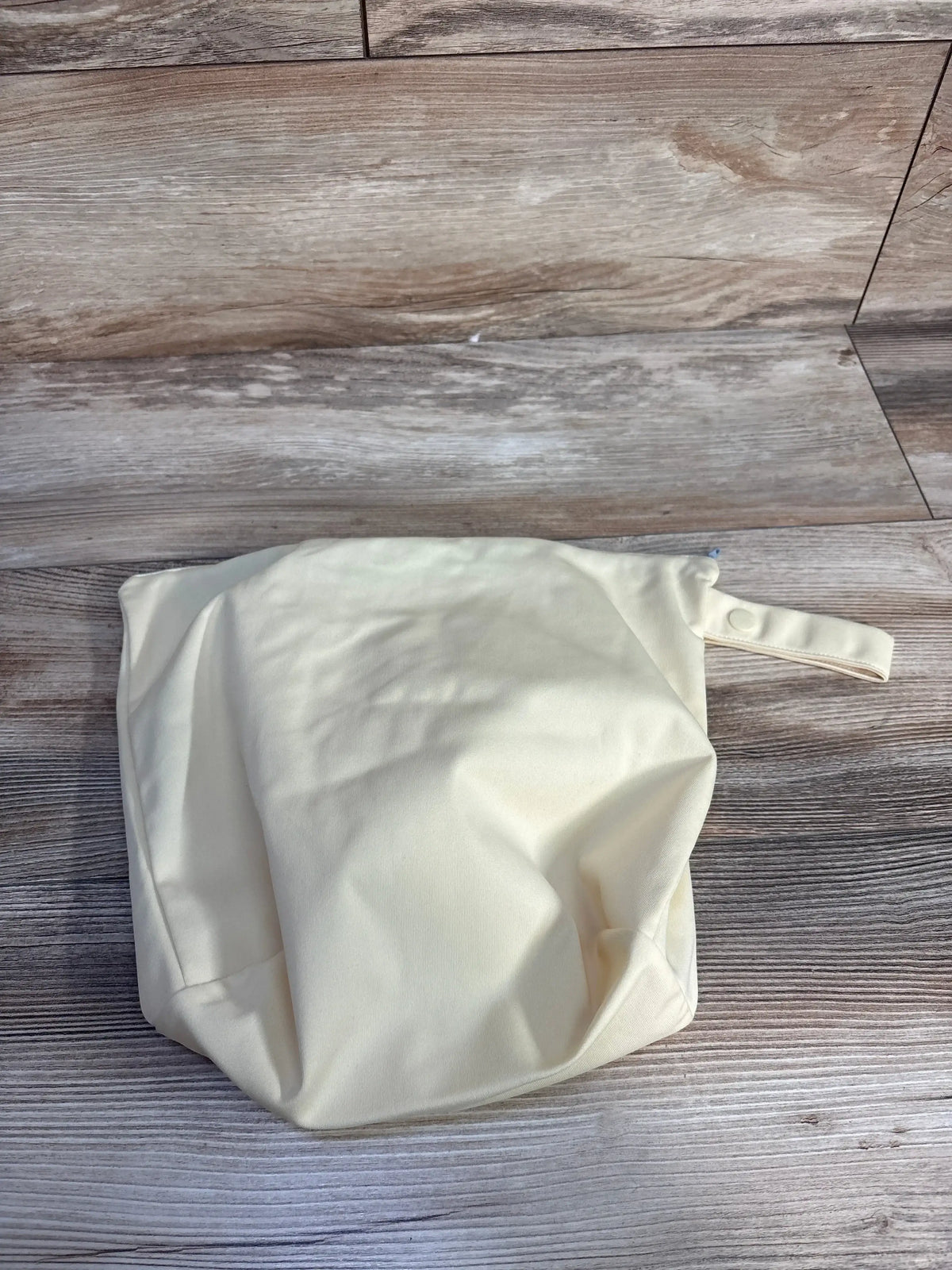 Top-down view of GroVia zippered wet/dry bag showcasing waterproof fabric and snap wrist strap with wood background