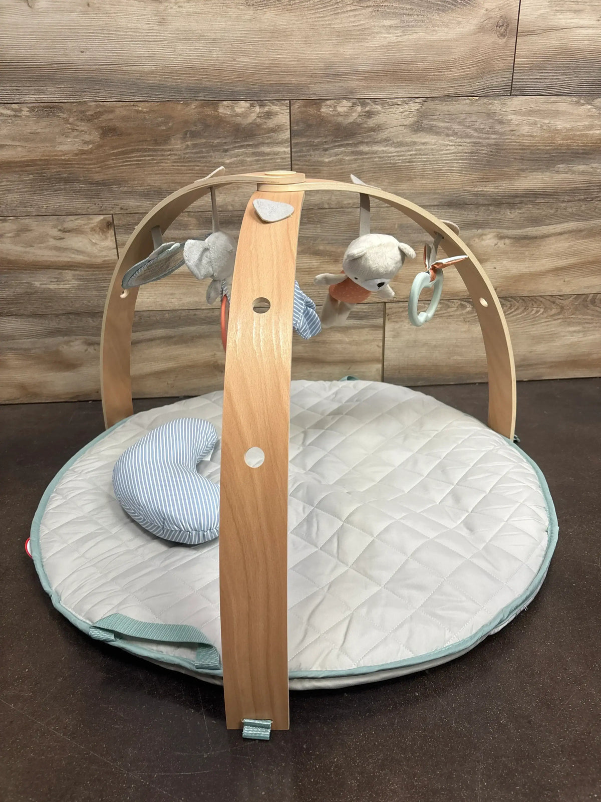 Wooden baby activity gym with plush toys and a quilted play mat