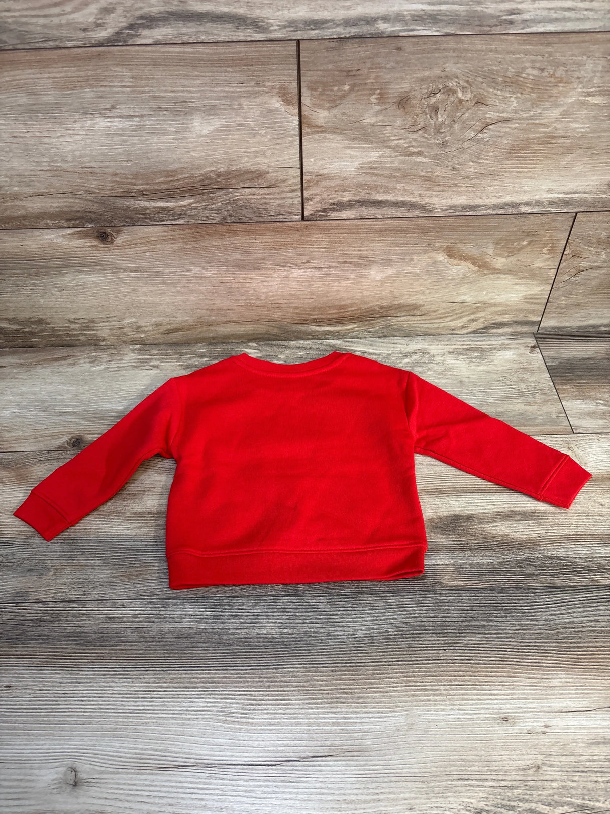 Red long sleeve toddler sweatshirt displayed on wooden floor