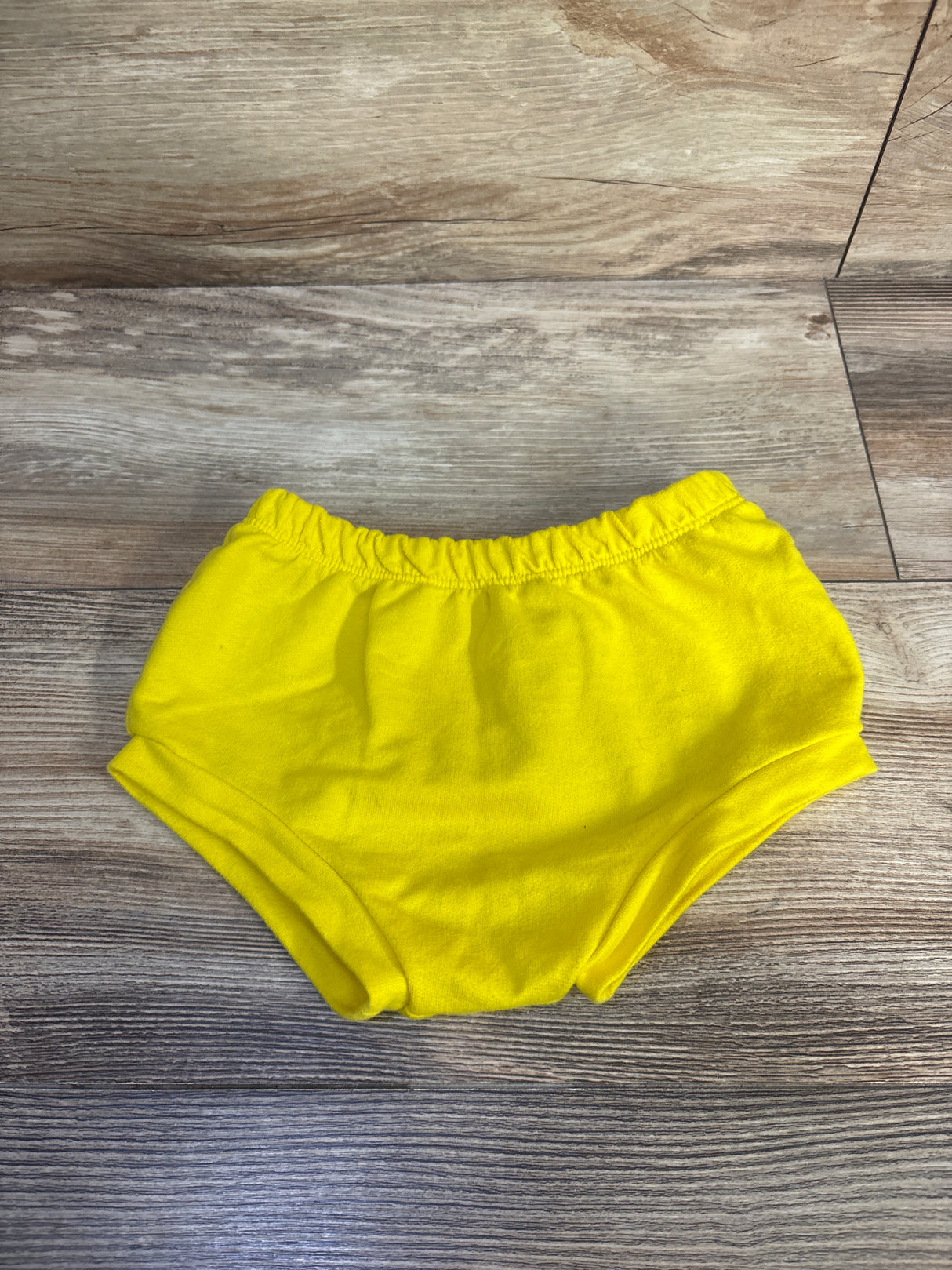 Front view of yellow Cat and Jack bloomers in size 12 months with a relaxed fit and elastic waistband on a wood floor