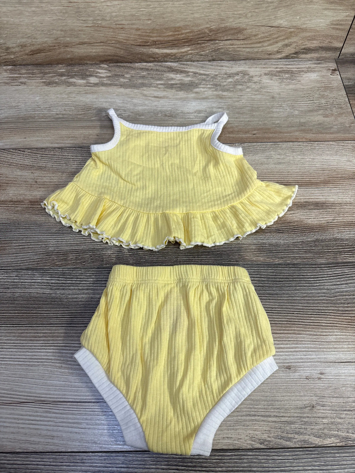 Top-down view of Cat & Jack yellow ribbed peplum tank top and bloomers set with white trim on wood background