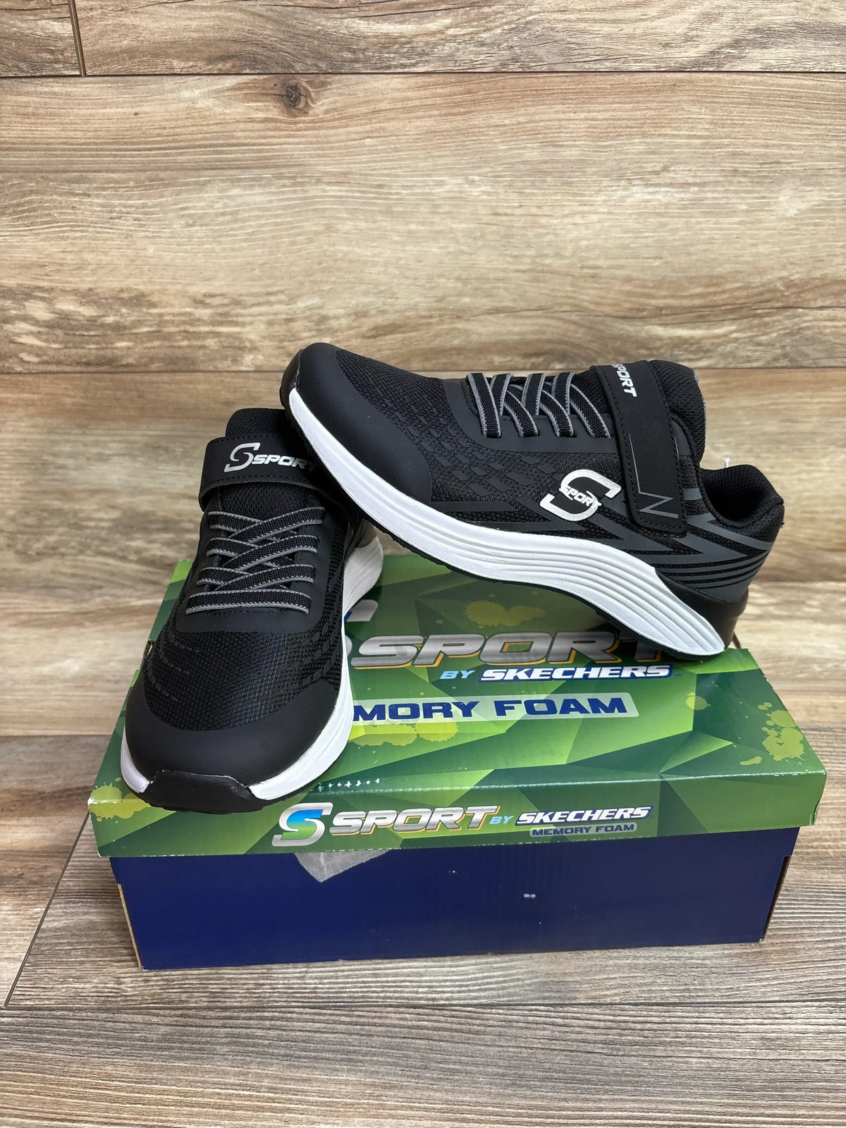 Black S Sport by Skechers memory foam sneakers on box, wood background