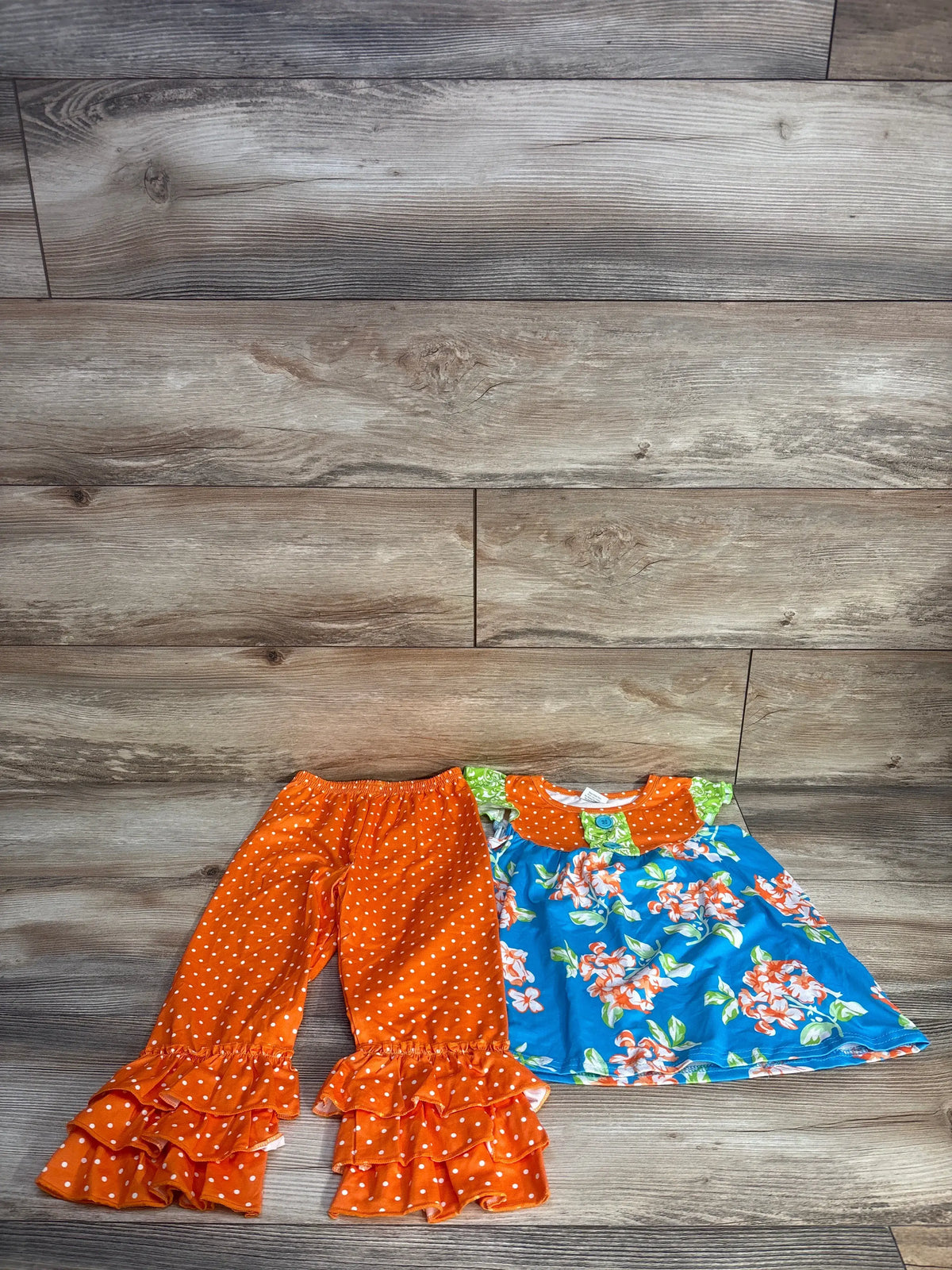 Front view of Waverly Scarlet 2pc dress set with orange polka dot ruffle pants and blue floral dress on wood background