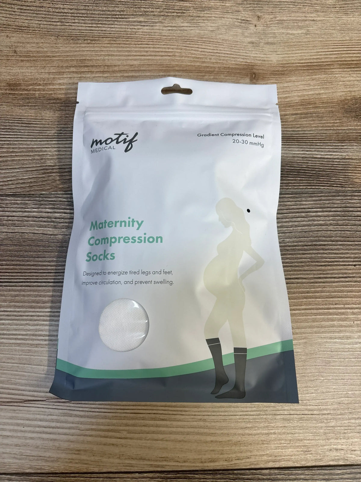 Motif Medical maternity compression socks packaging on wooden surface, designed for pregnancy support