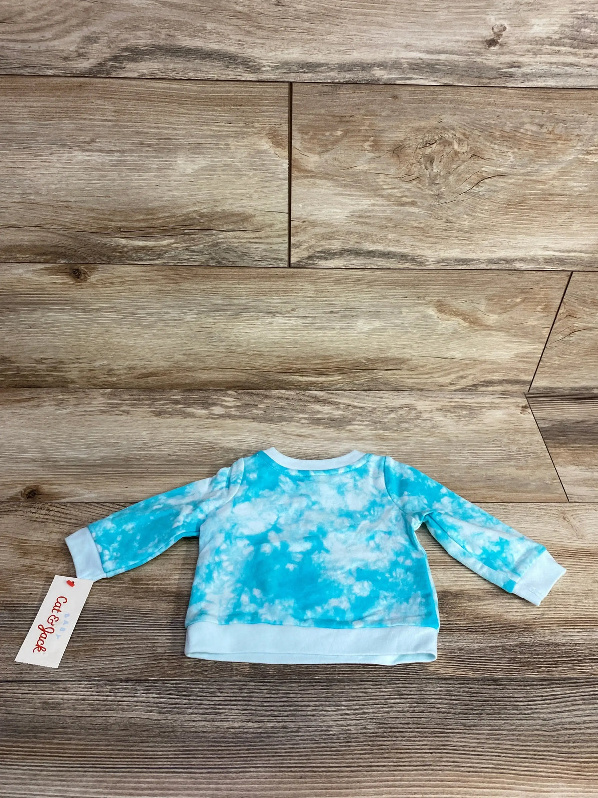 Blue and white tie dye long sleeve baby shirt on wooden floor