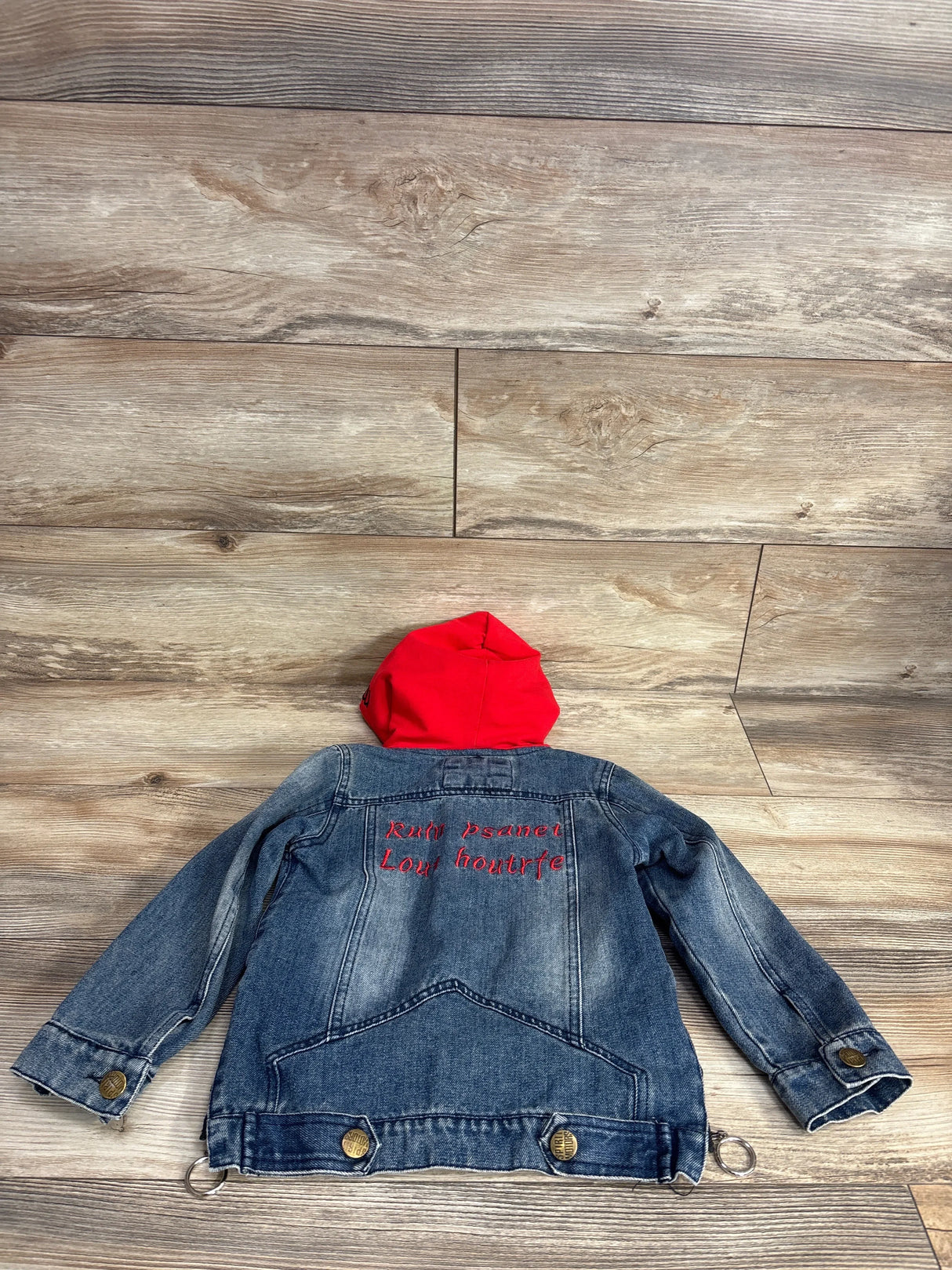 Kids denim jacket with red hood, embroidered back, laid on wood floor, children's outerwear