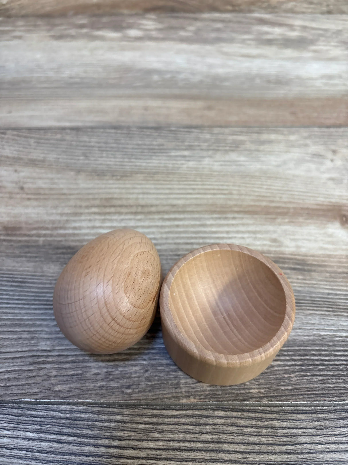 Natural wooden egg-shaped toy container on rustic wood background