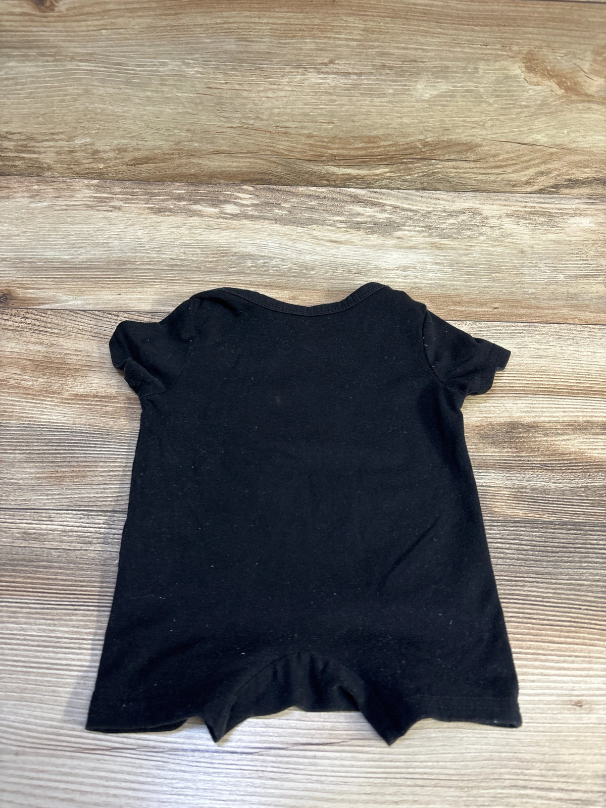 Back view of Shein Just A Boy Who Loves His Mom shortie romper showcasing short sleeves on wood grain