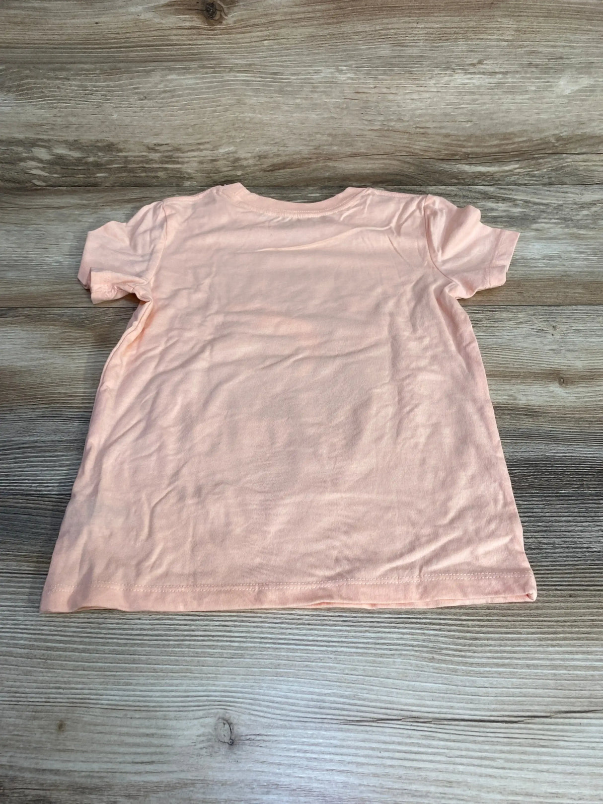 Back view of peach Cat & Jack toddler shark t-shirt showing short sleeves and plain back on light wood background