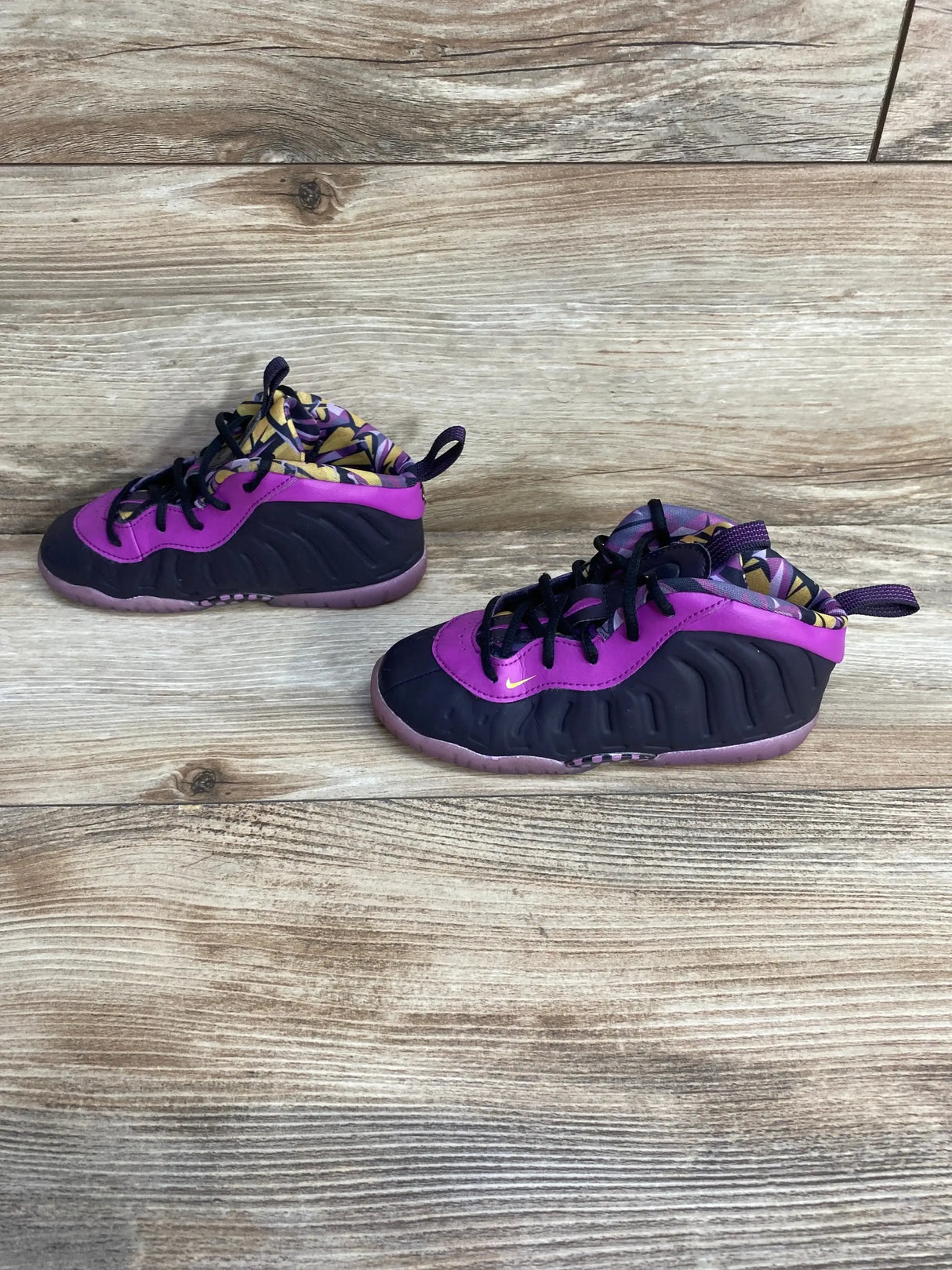 Side view of Nike Little Posite One toddler sneakers in cave purple and black showing foam upper and patterned lining on wood surface