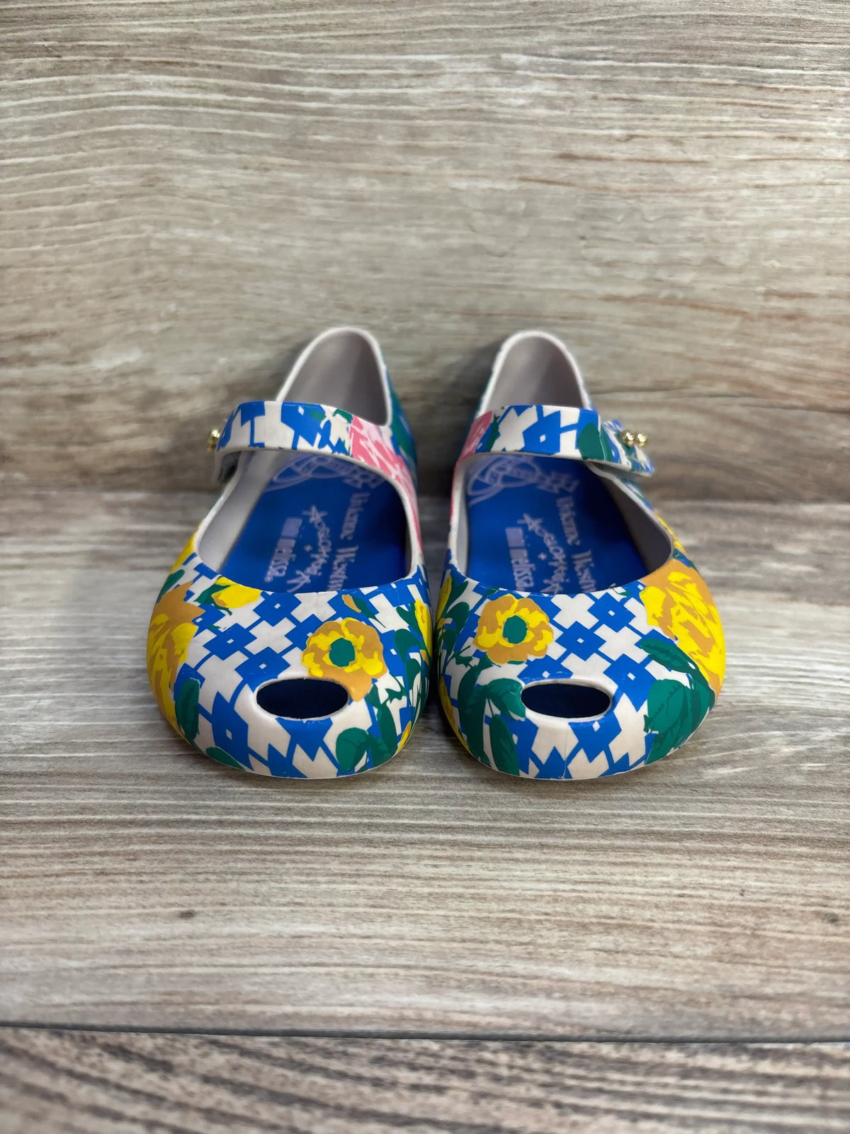 Front of Vivienne Westwood x Melissa Mary Jane shoes, blue-and-white print with yellow flowers and toe cutouts on wood background