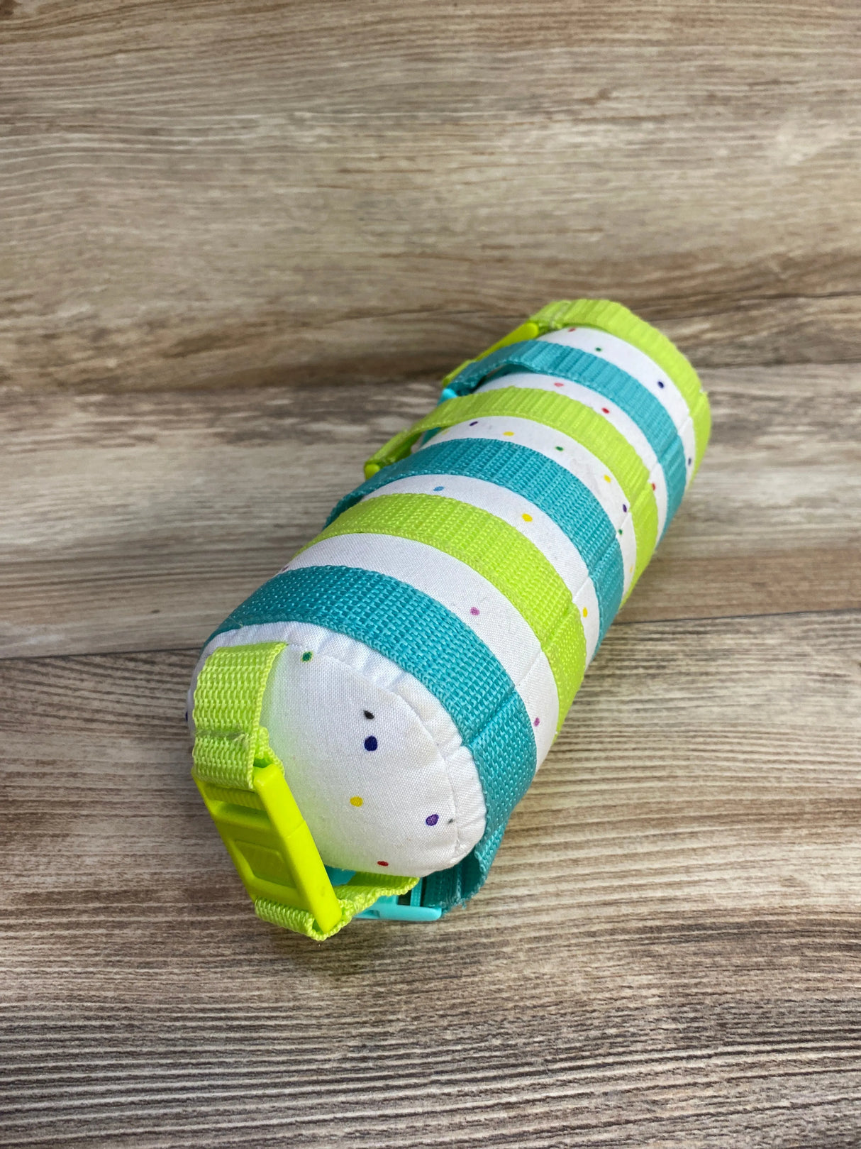 Striped fabric roll with blue, yellow, and white colors and dotted pattern on wooden surface