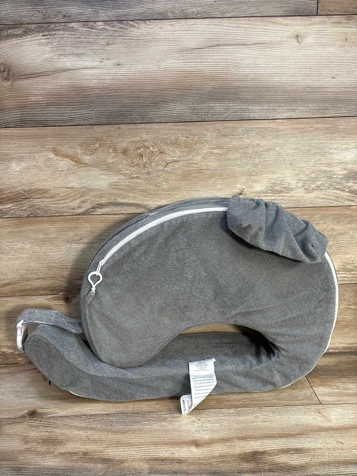 Top view of My Brest Friend nursing pillow slipcover in grey showing its wraparound shape, zipper, and adjustable strap on wood
