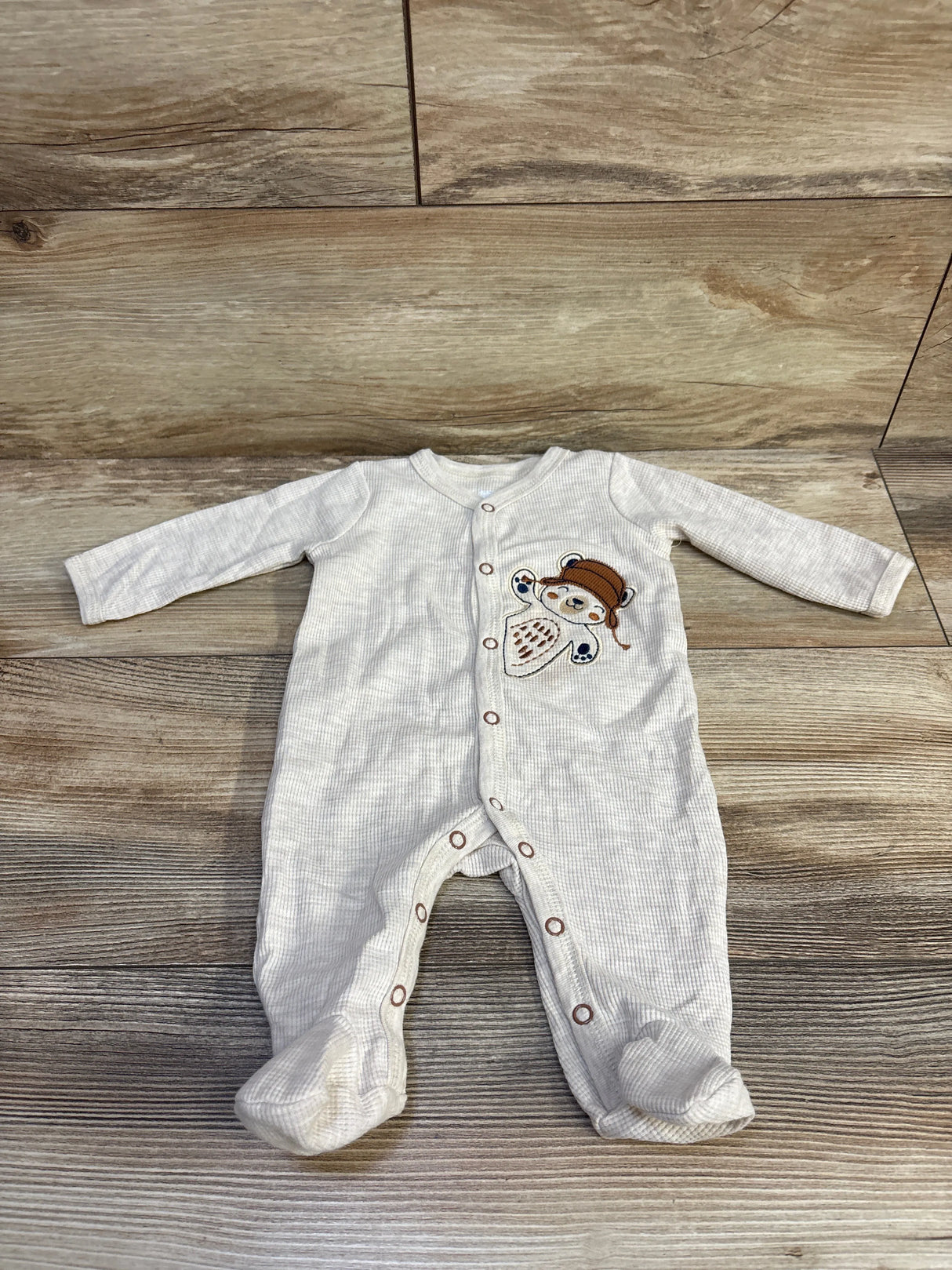 Top-down view of Koala Baby waffle knit snap sleeper showcasing front snap closure, embroidered bear patch, and built-in feet on wood floor