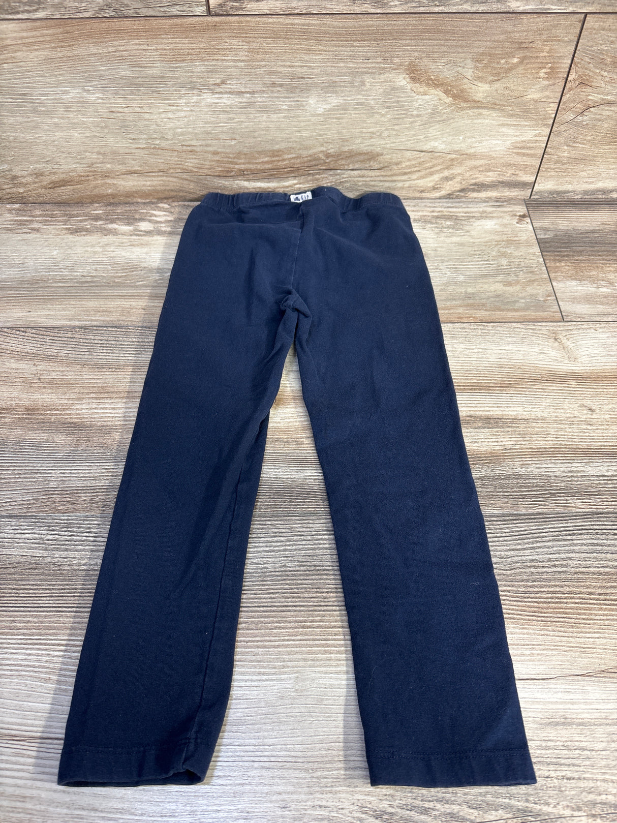 Front flat lay of Baby Gap navy leggings size 4T showcasing elastic waistband and straight full-length legs on light wood floor