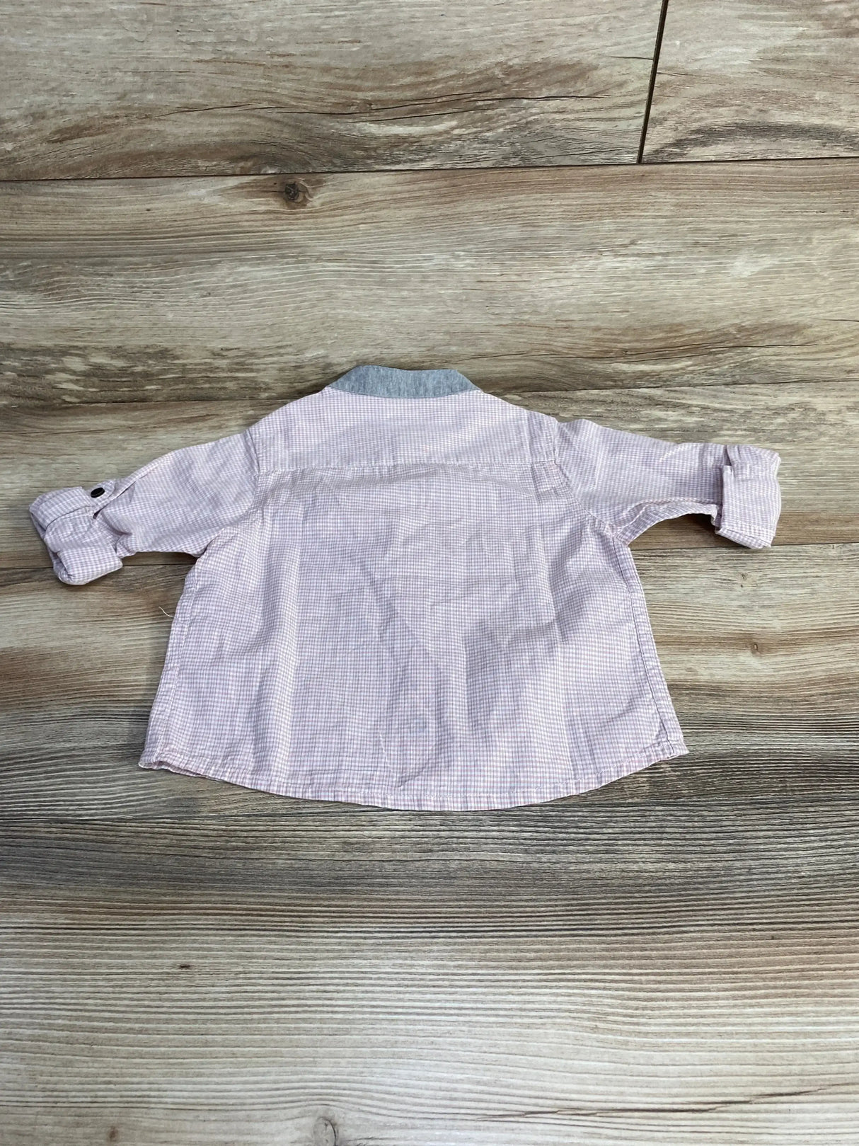Back view of pink Crib Couture button-up shirt size 12 months showing rolled sleeves and gray knit collar on wood floor background