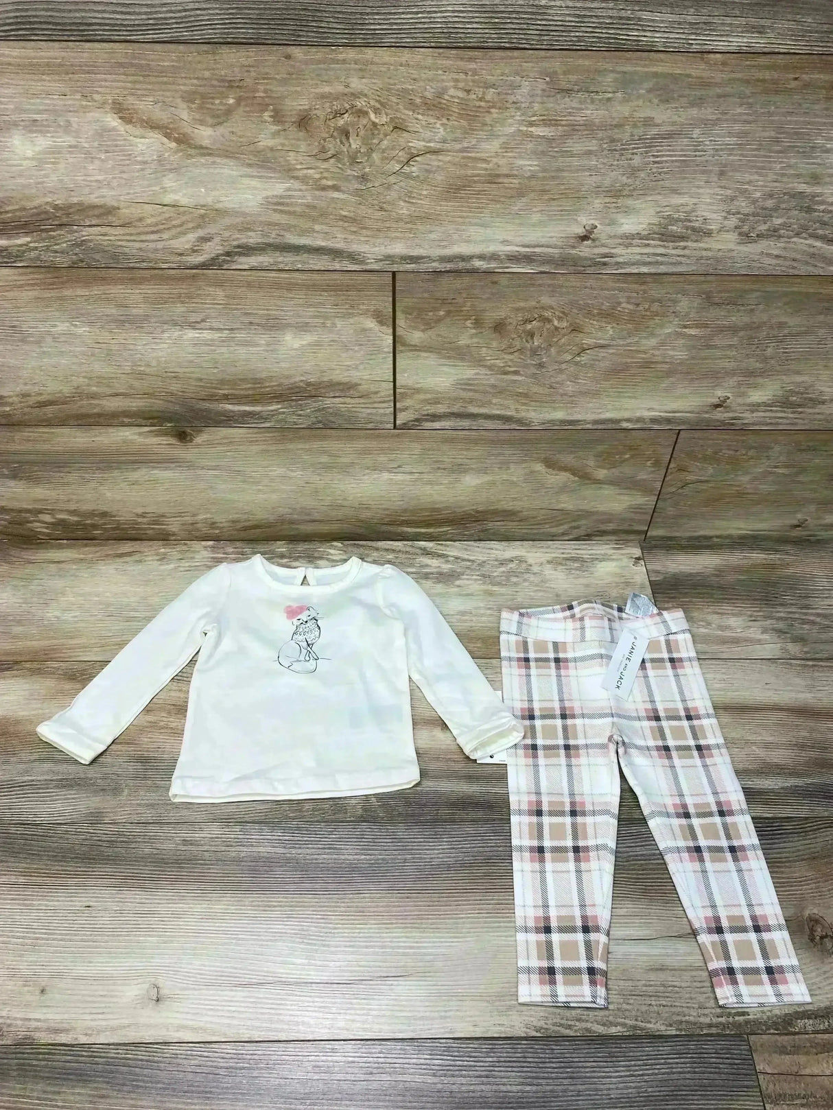 Flat lay of cream long sleeve fox tee and pink beige plaid ponte pants showing fox graphic and waistband on wood background