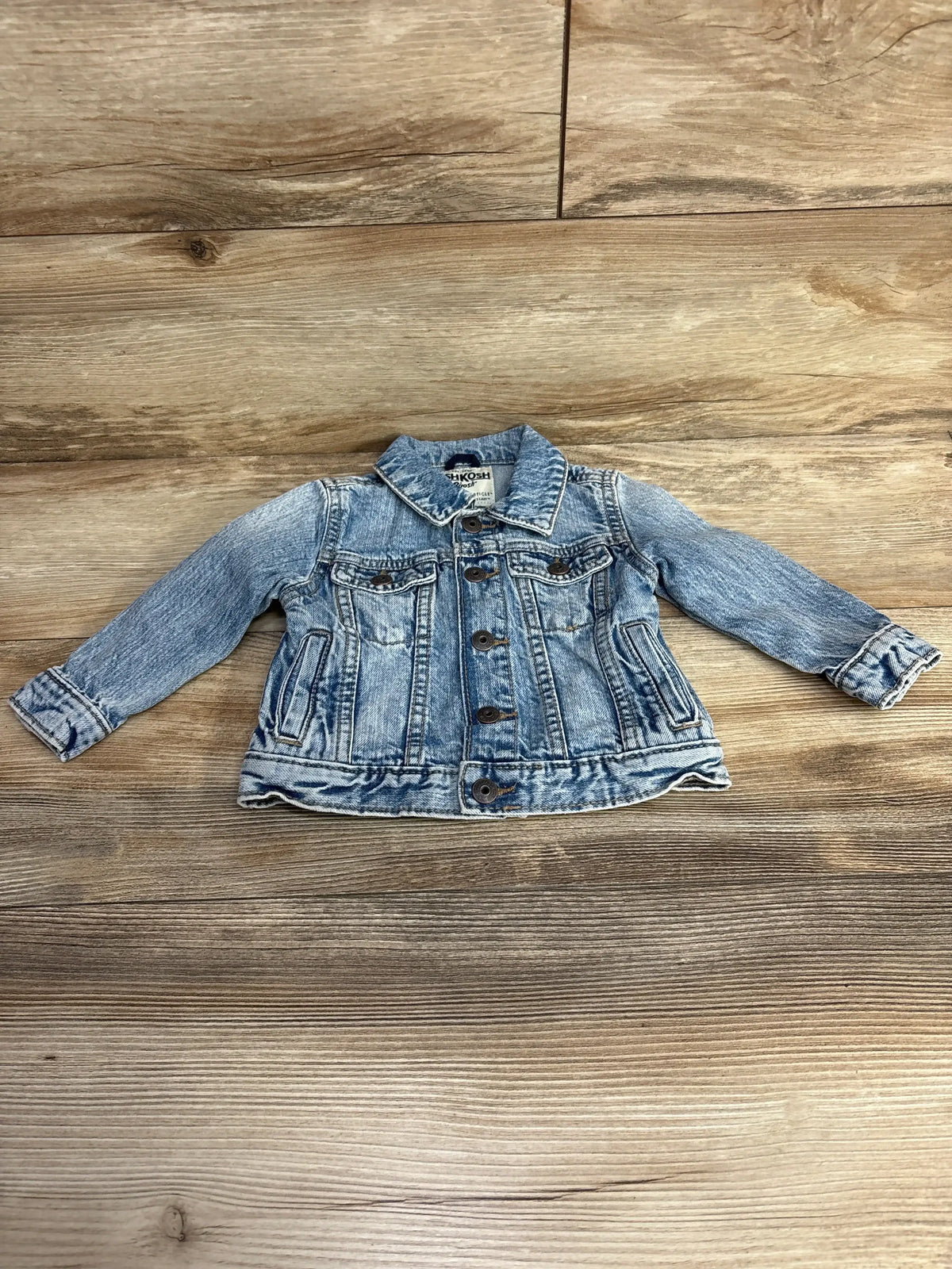 Light blue OshKosh B'gosh toddler denim jacket with buttons on wooden background