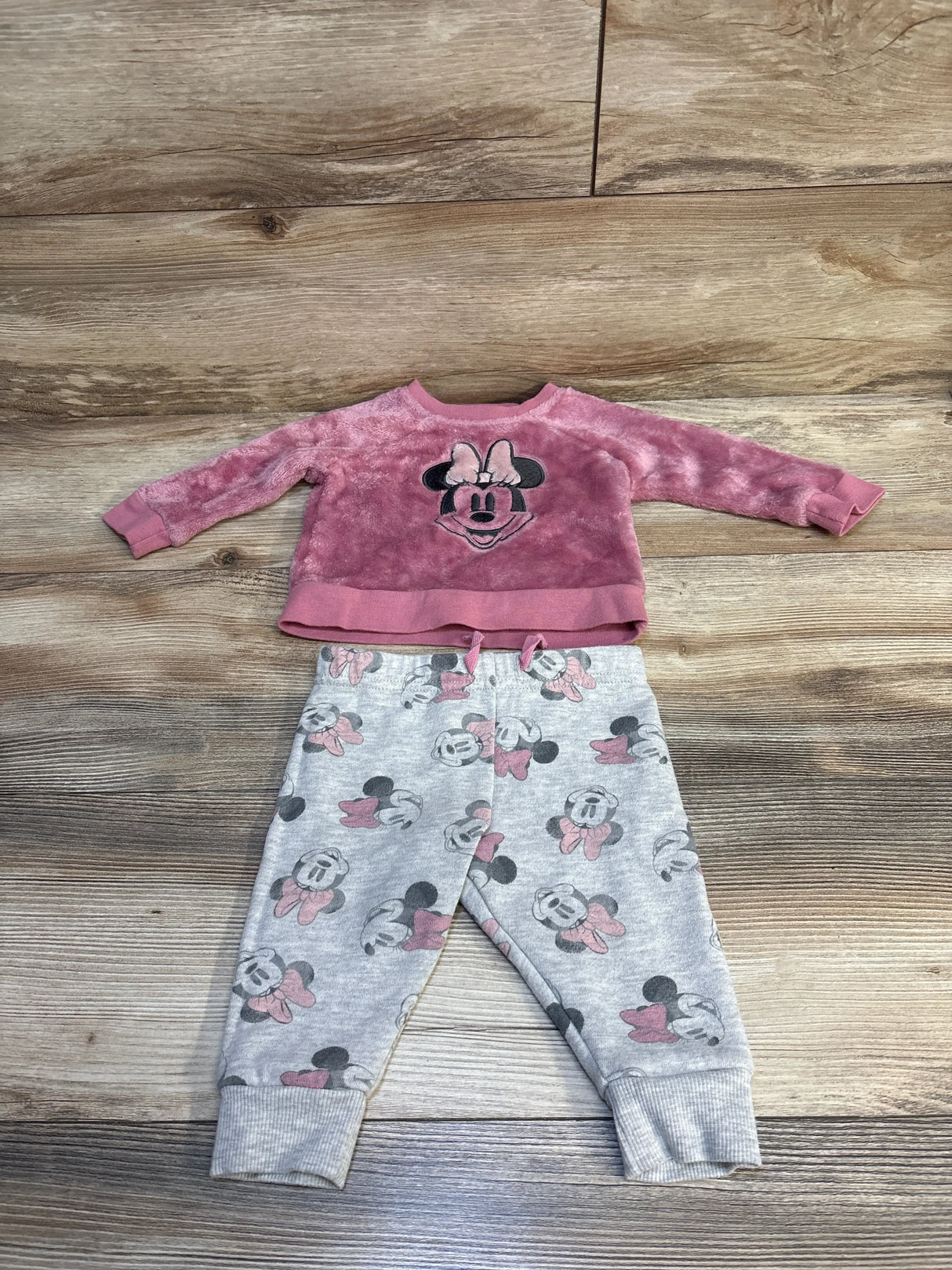 Pink Minnie Mouse toddler sweater and matching gray jogger pants set on wooden floor