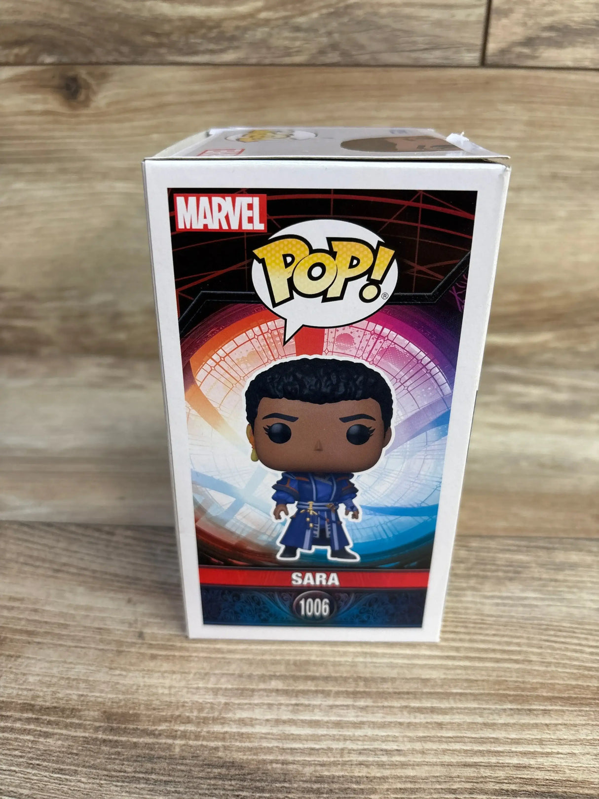 Front view of Funko Pop box for Sara with large POP and Marvel logos and Sara nameplate on wood background