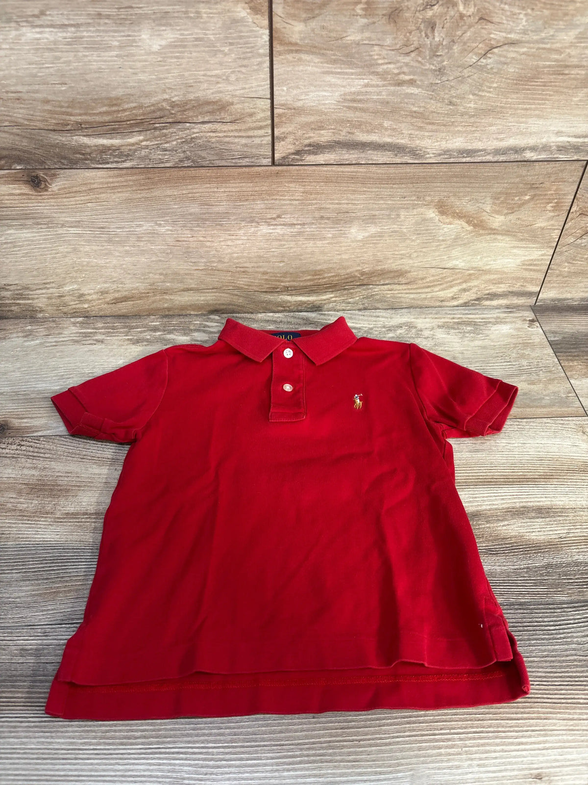 Front view of red Polo Ralph Lauren polo shirt in size 3T with collar, button placket, and embroidered logo on wood flooring