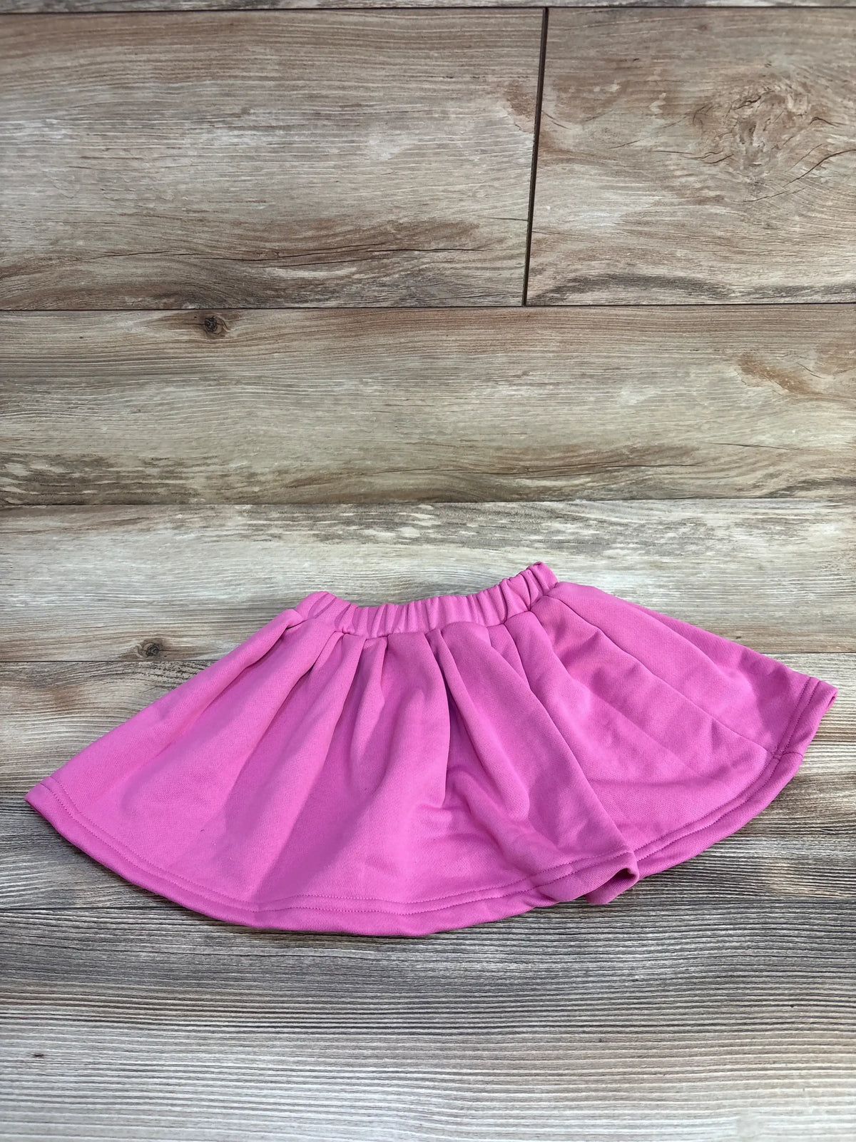 Pink cotton girls skirt with elastic waistband on wood background