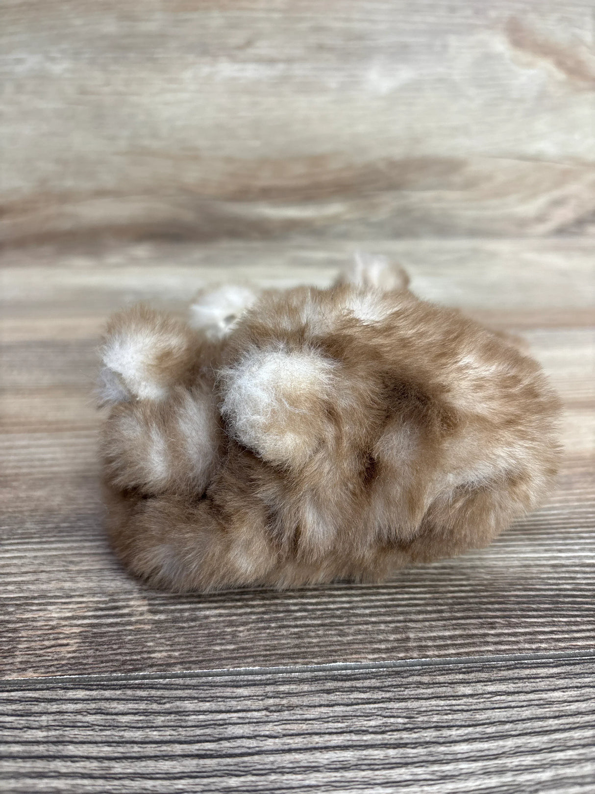 Soft brown and white baby mittens on wooden surface from children's resale store