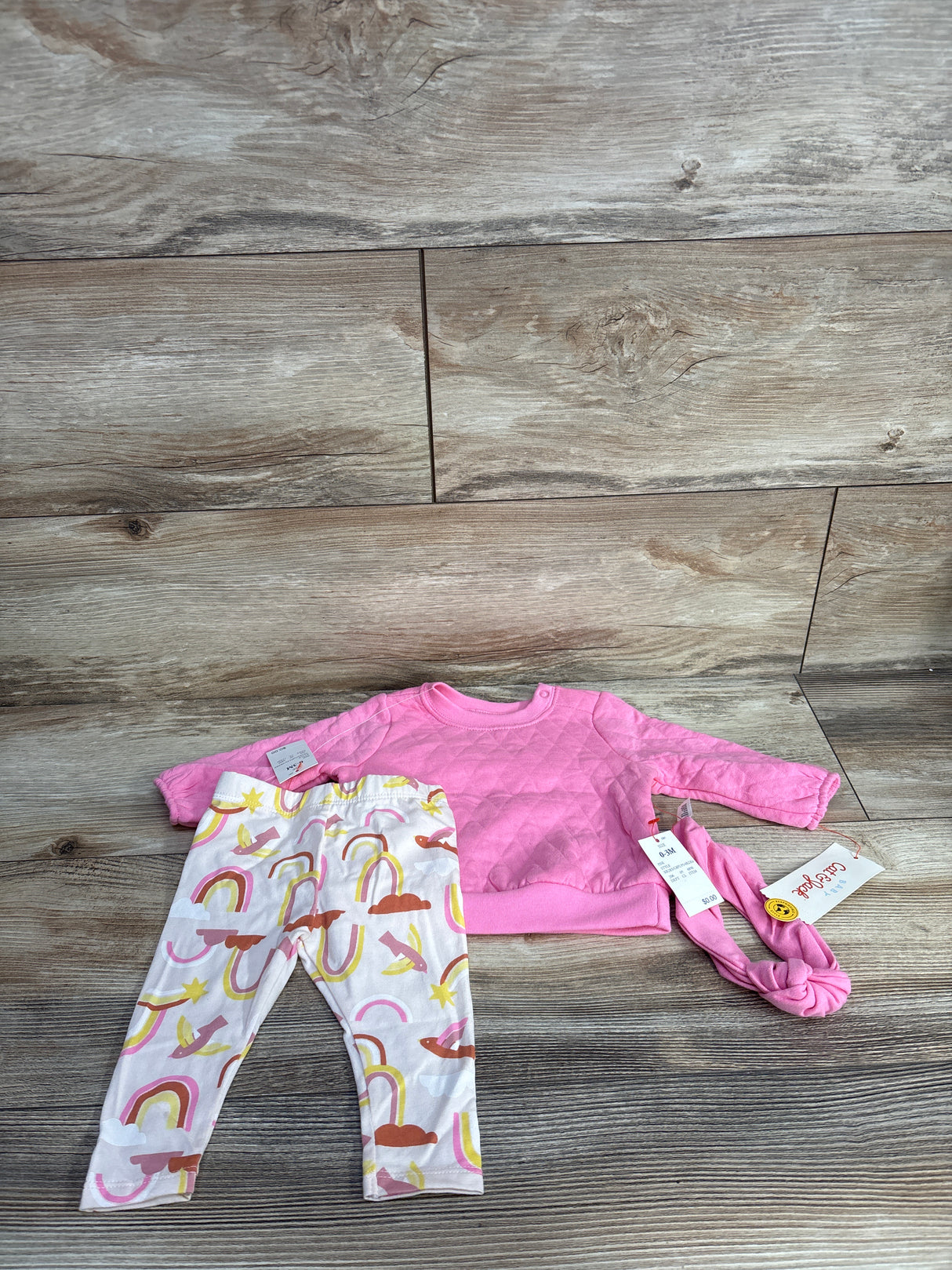 Infant 0-3 months pink quilted sweater, rainbow patterned leggings, and matching pink headband on wood floor