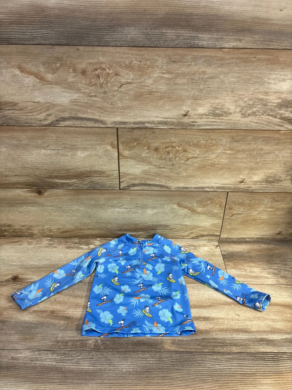 Front view of Zara x Peanuts long sleeve quarter-zip rash guard top showcasing blue character print on a wood-look floor