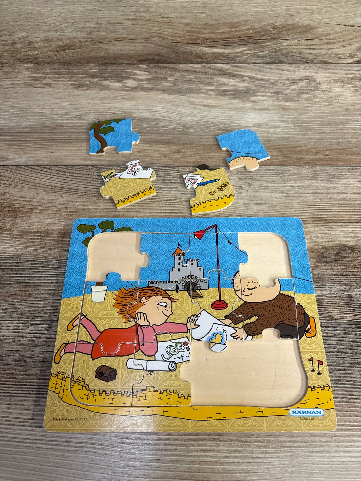 Children's wooden jigsaw puzzle with playful kids building a sandcastle on the beach, partially assembled.