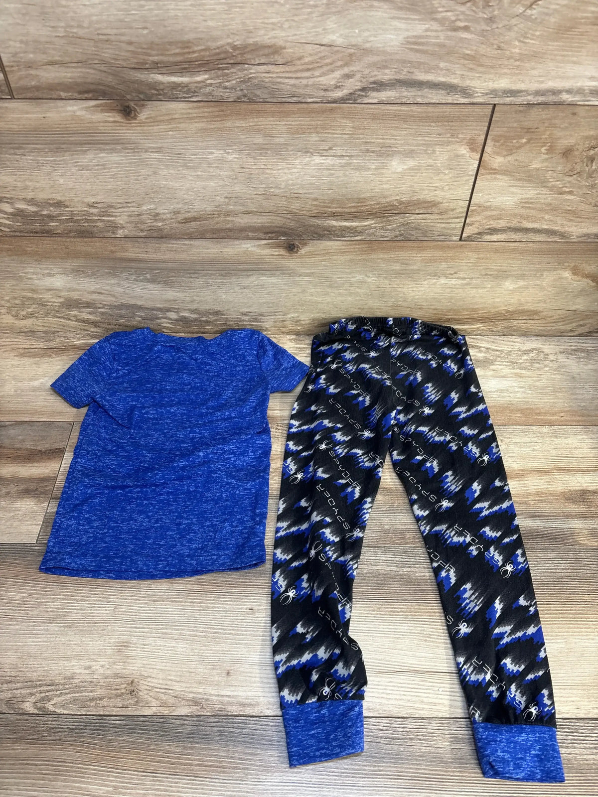 Blue short sleeve kids shirt and patterned blue black pajama pants set on wood floor