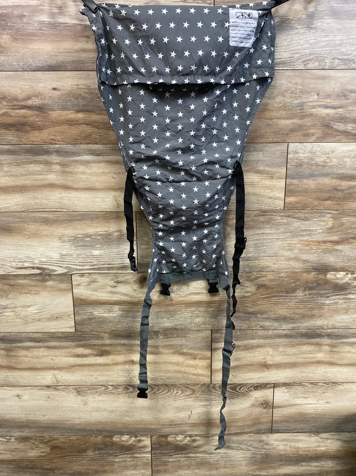 Front view of baby high chair safety harness in grey star print showing adjustable straps and buckles on wooden floor