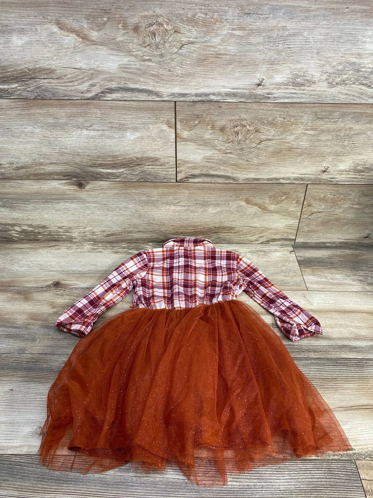 Girls plaid long sleeve dress with orange tulle skirt on wood background