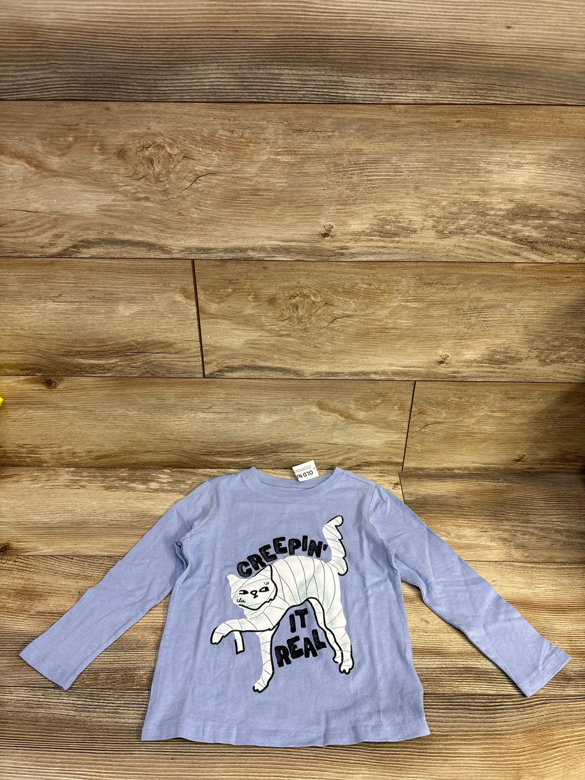 Front view of blue Old Navy Halloween shirt showcasing a mummy graphic and Creepin It Real text on a wood floor