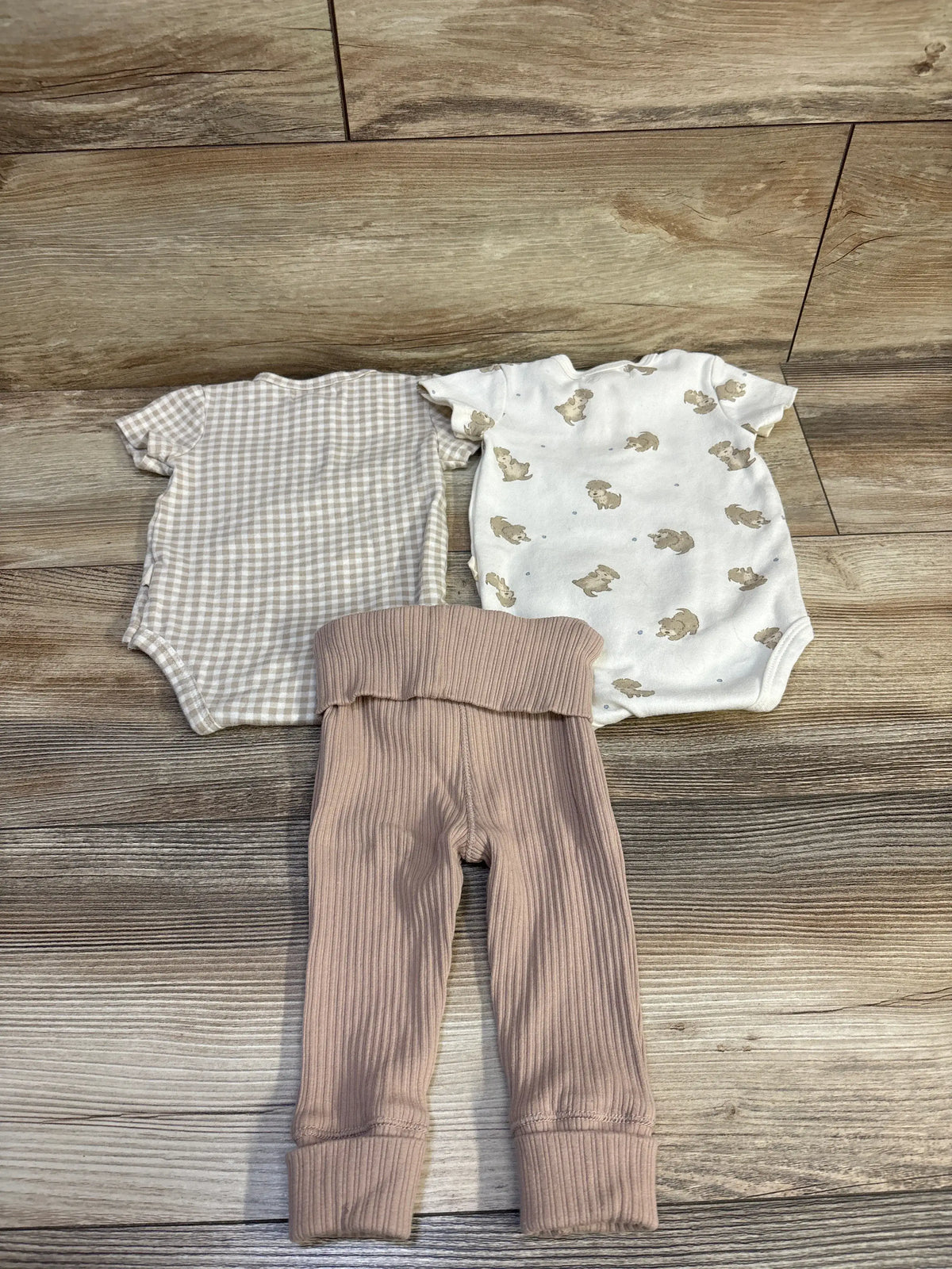 Top-down view of ivory Rabbit + Bear 3-piece bodysuit and pant set showing gingham, animal print, and ribbed pieces