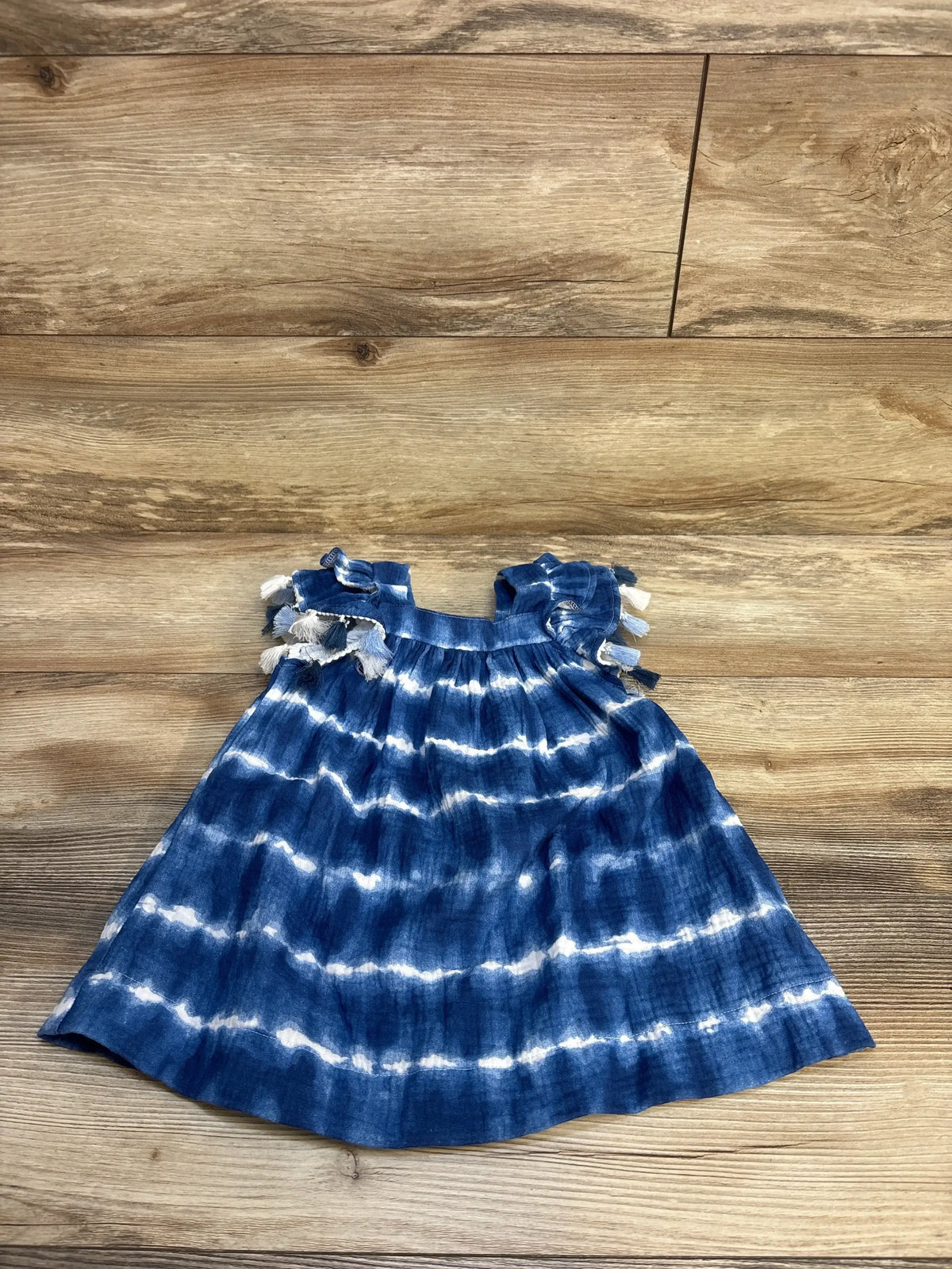 Blue and white tie dye baby dress with ruffle sleeves on wooden background
