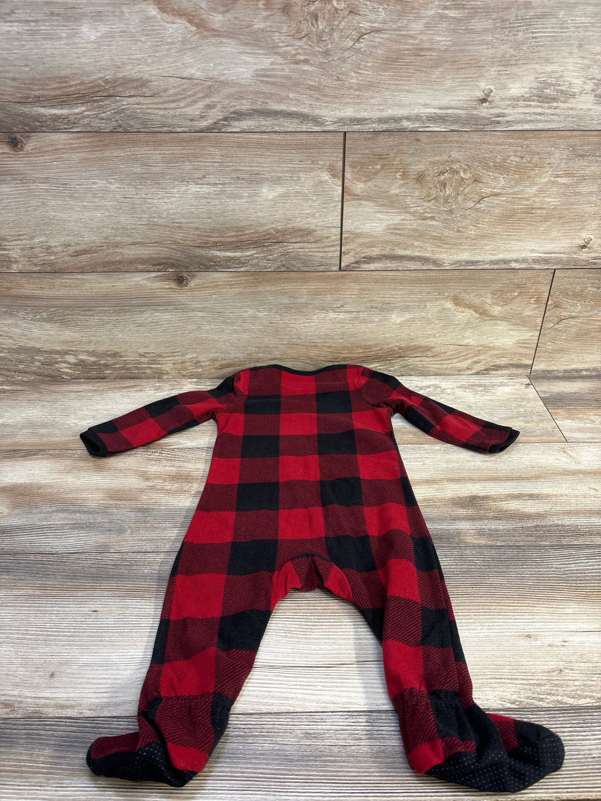 Flat lay of red and black buffalo plaid blanket sleeper (12 months) showing footed legs and long sleeves on light wood background