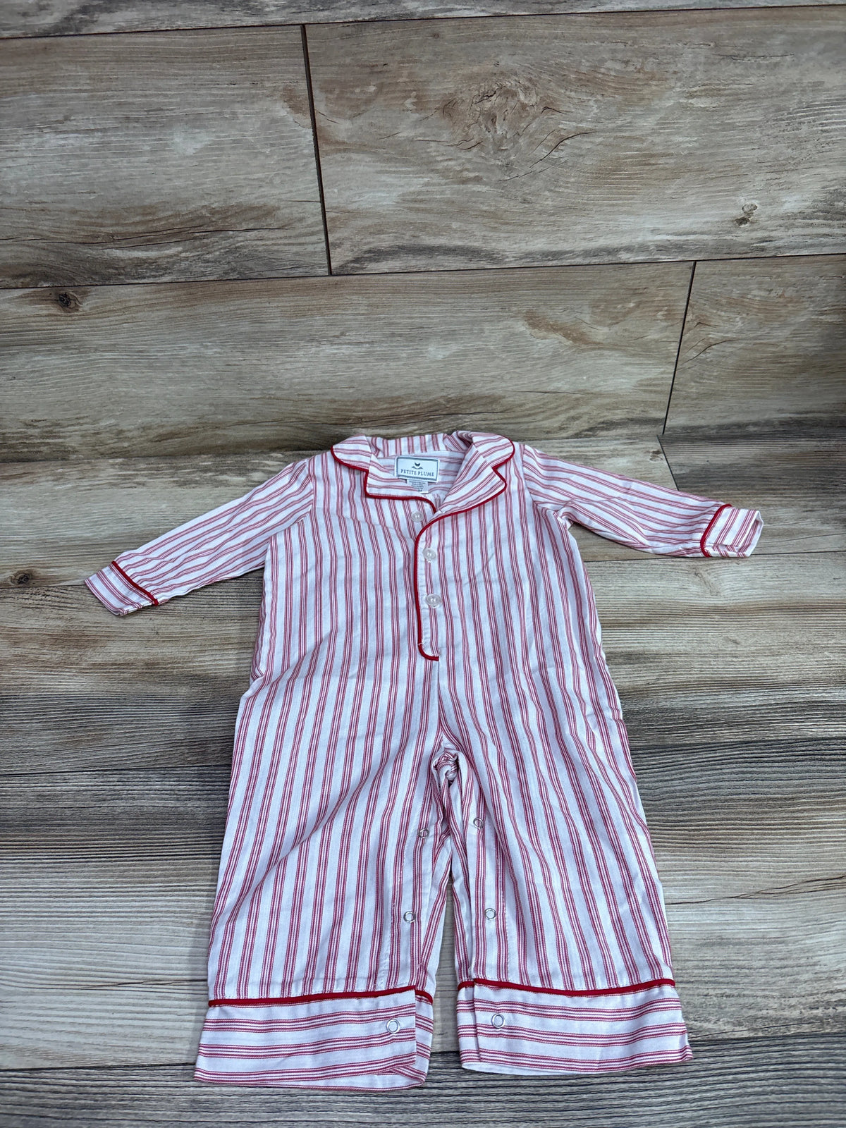 Front view of Petite Plume romper showcasing antique red ticking stripes, collar, long sleeves, and button front on wood floor