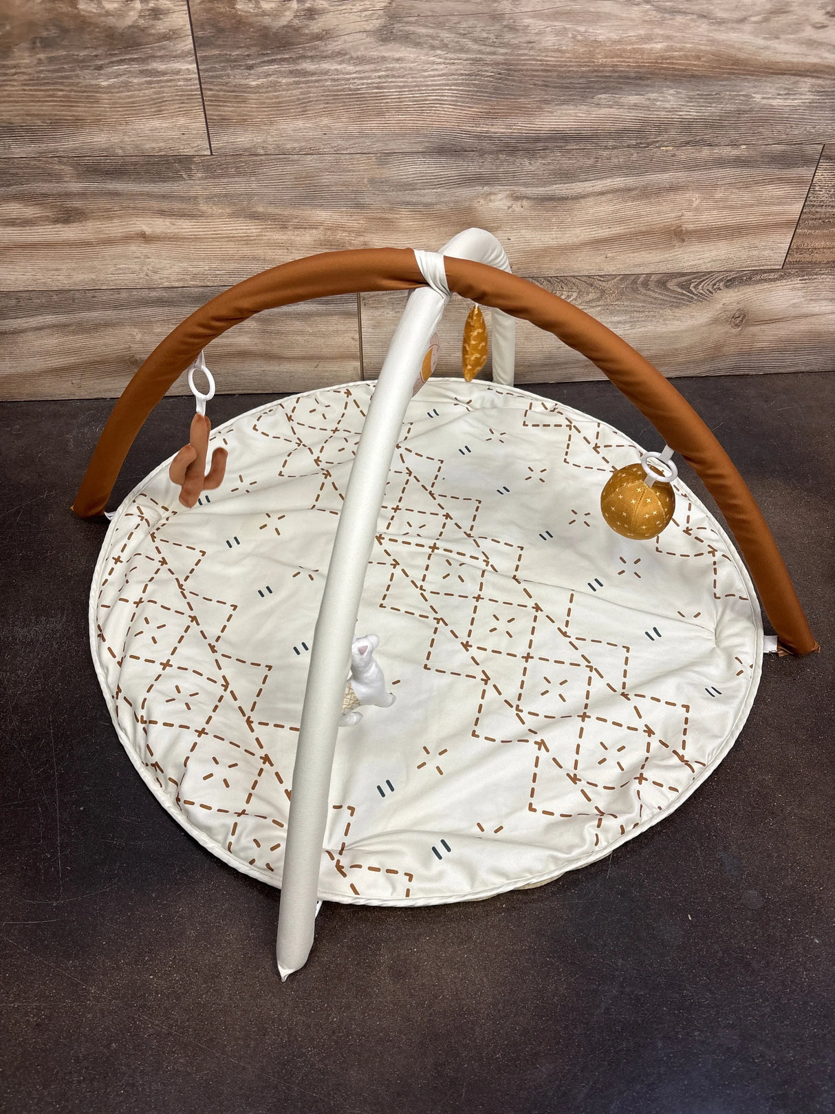 Baby play gym with hanging toys and patterned mat, great for infant development.