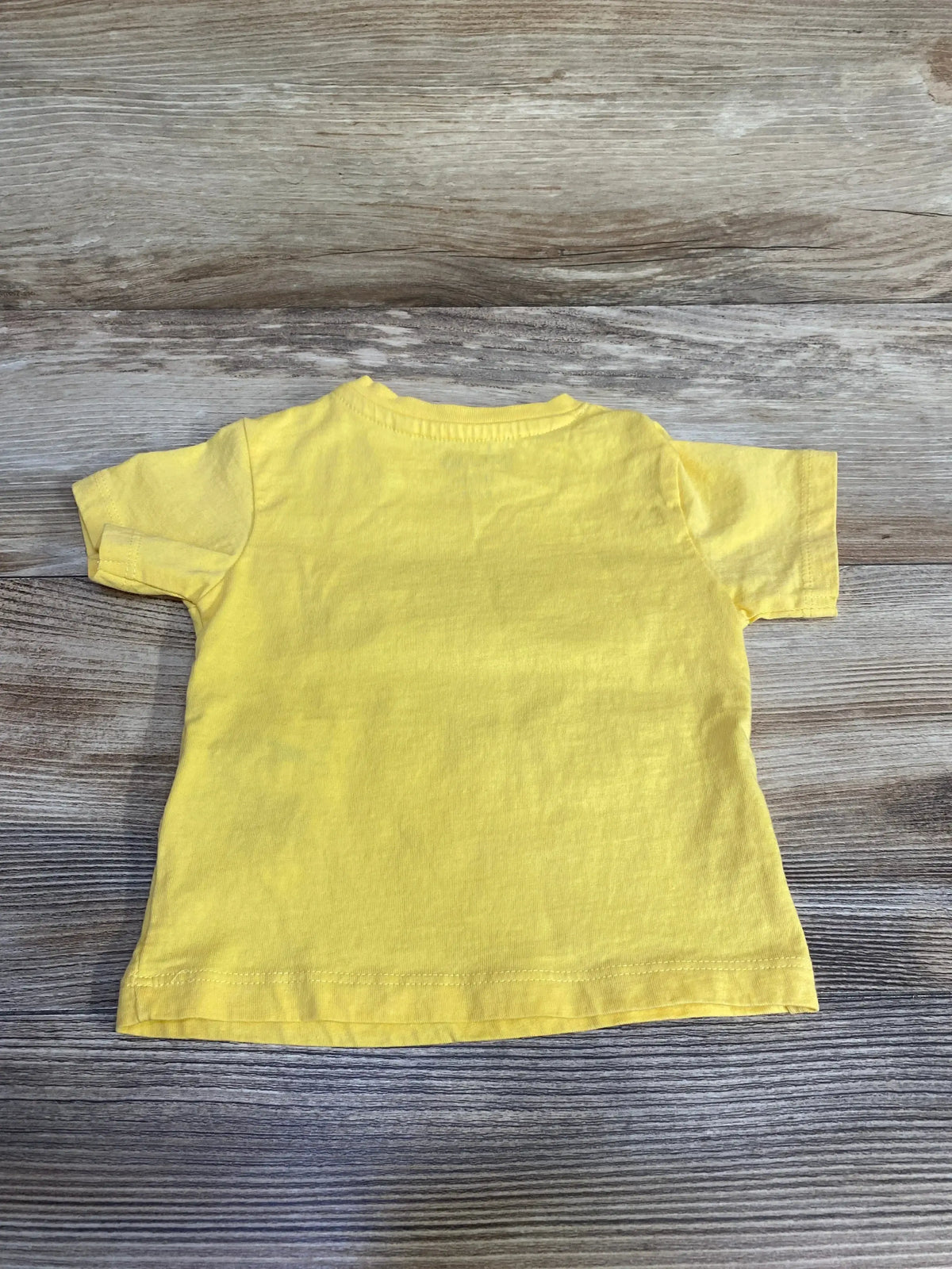 Back view of MO Kids Ciao Buddy baby t-shirt showcasing short sleeves and plain back with wood-grain background