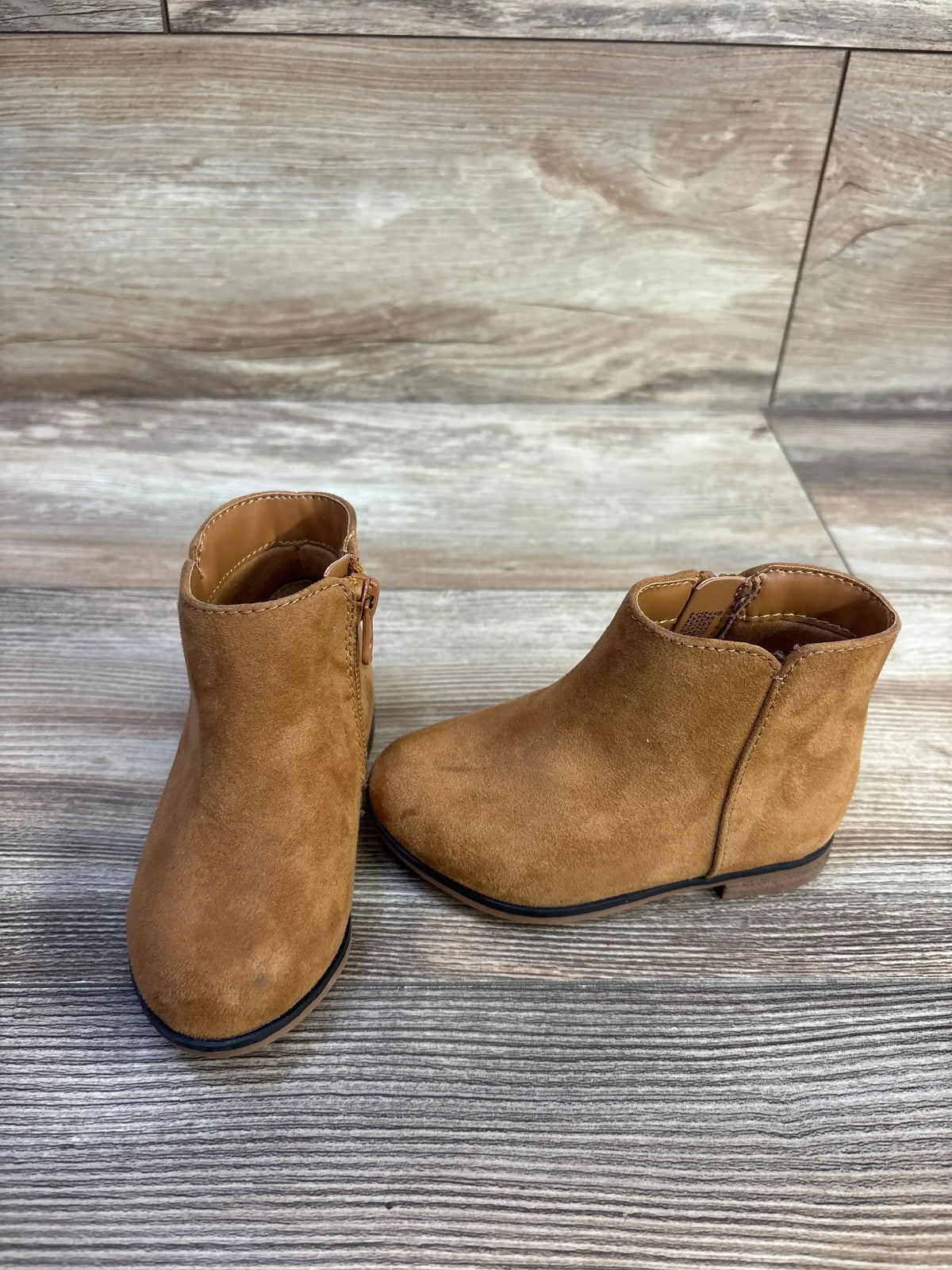 Three-quarter view of Cat & Jack Penelope boots in brown, size 6C, showcasing side zippers on wood-look flooring