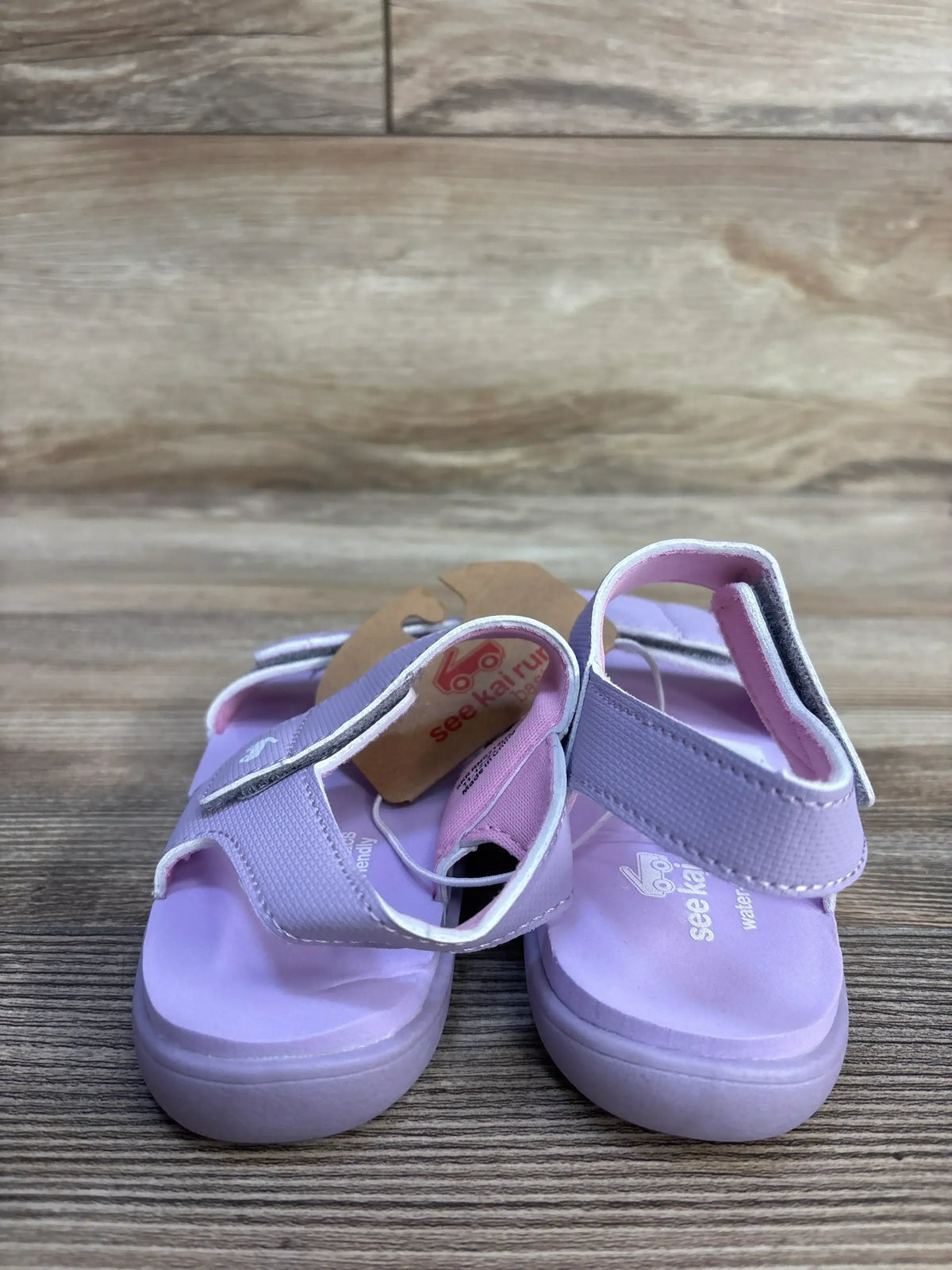 Front view of See Kai Run Jaylen toddler sandals showcasing lavender Velcro straps and cushioned sole on wood floor