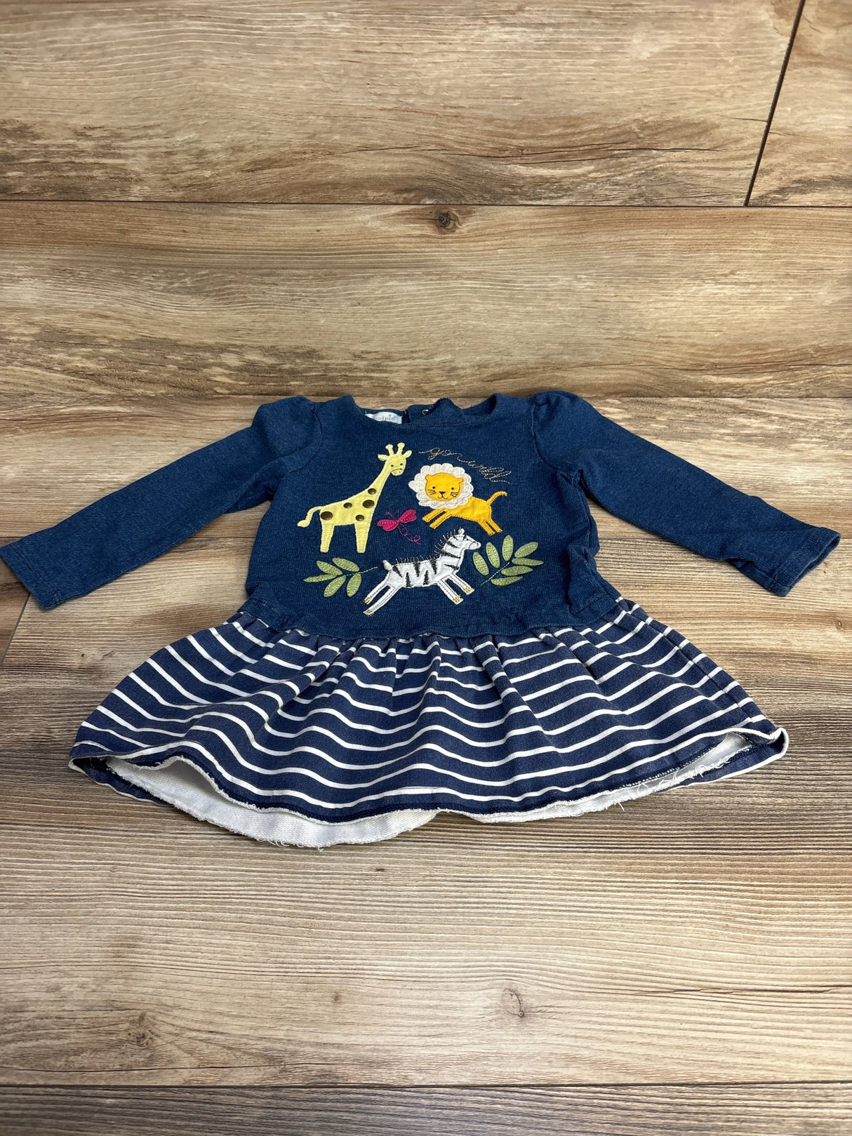 Front view of Mud Pie Animal Parade dress with embroidered giraffe, lion, zebra on navy top and navy-white striped skirt on wood